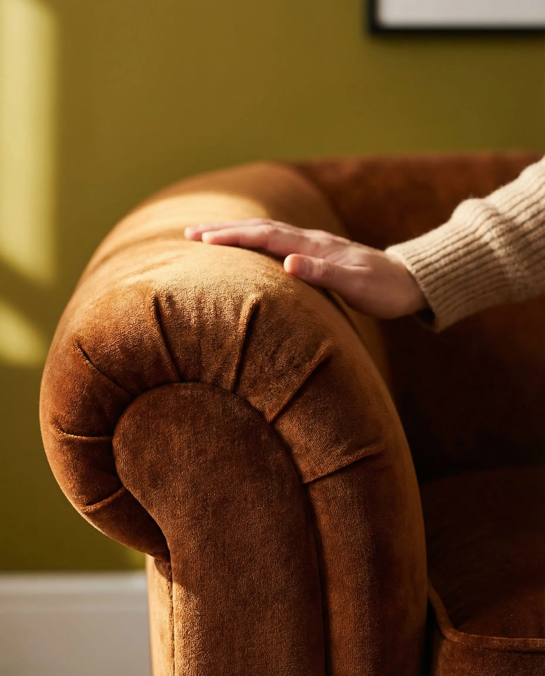 Detail shot of spiced caramel velvet fabric on a curved sofa arm.
