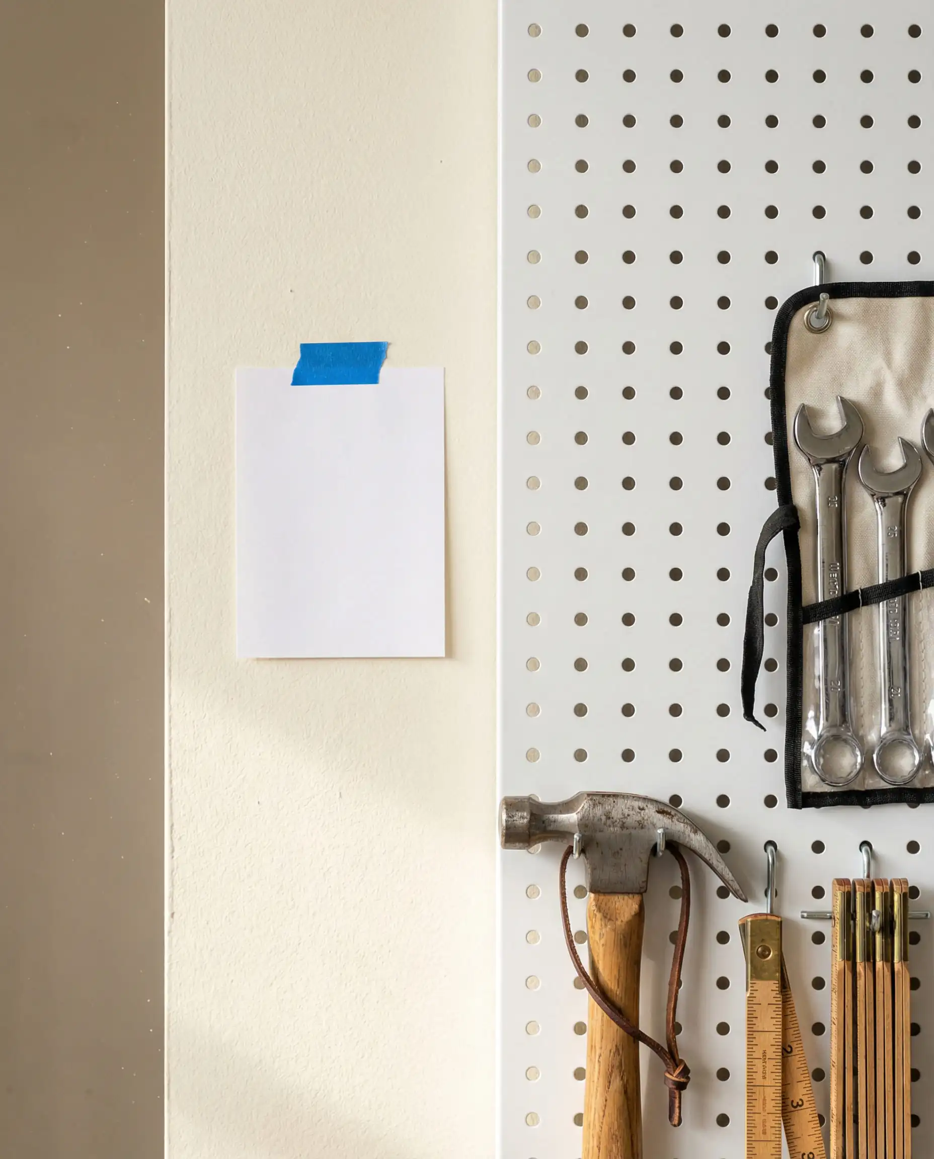 Close-up of a white metal pegboard with wooden tools on a garage wall painted in Swiss Coffee, showing the creamy undertones compared to bright white paper.