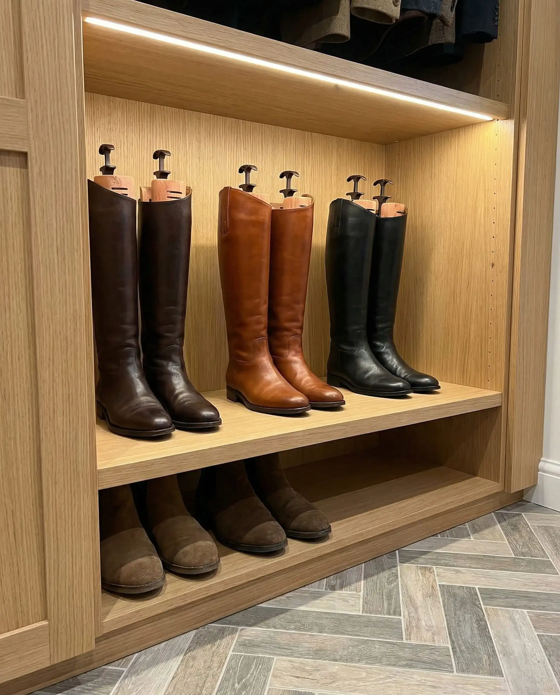 Dedicated tall shelving section for leather riding boots standing upright with boot shapers.
