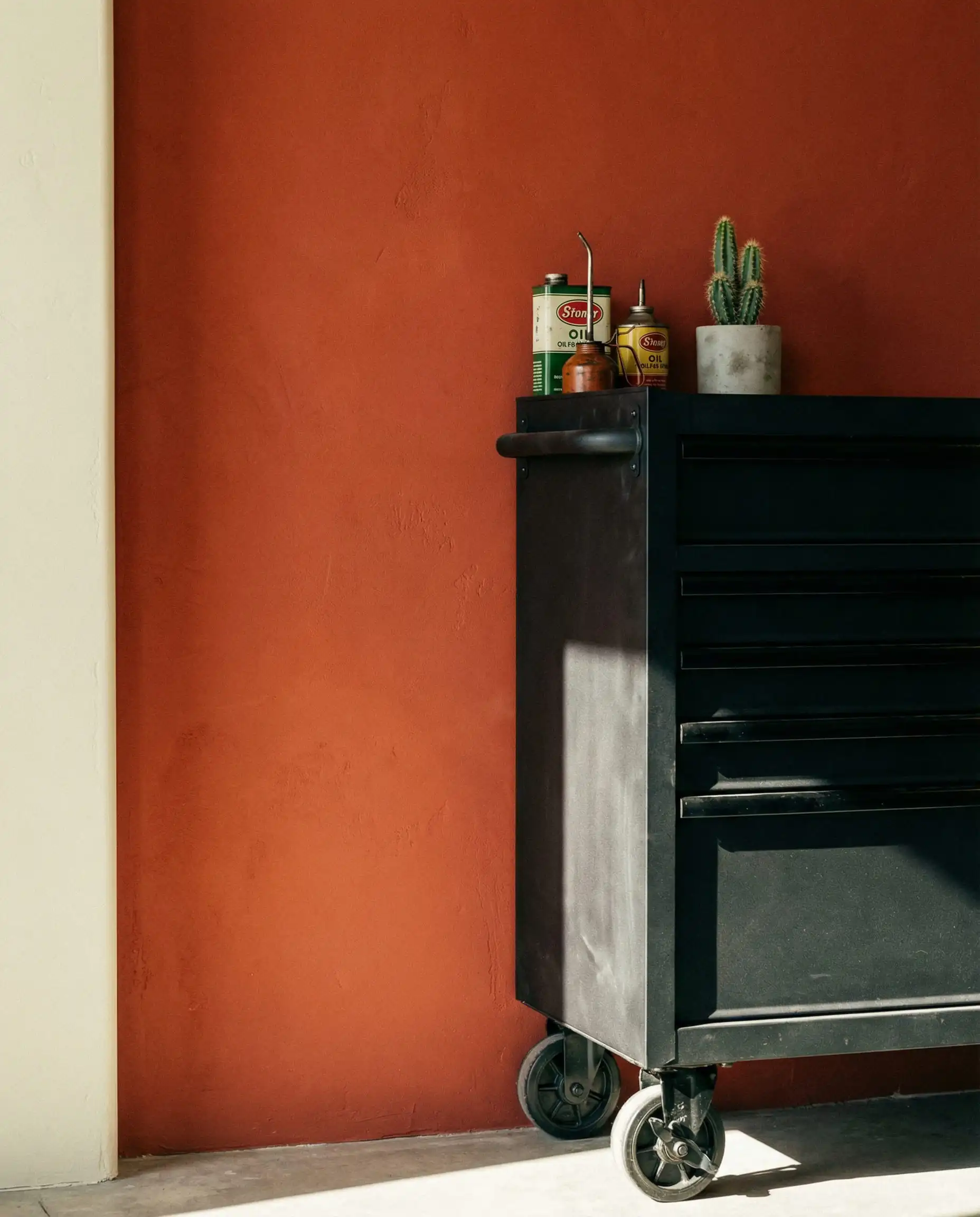 Bold terracotta accent wall in a garage contrasting with a black industrial rolling tool chest.