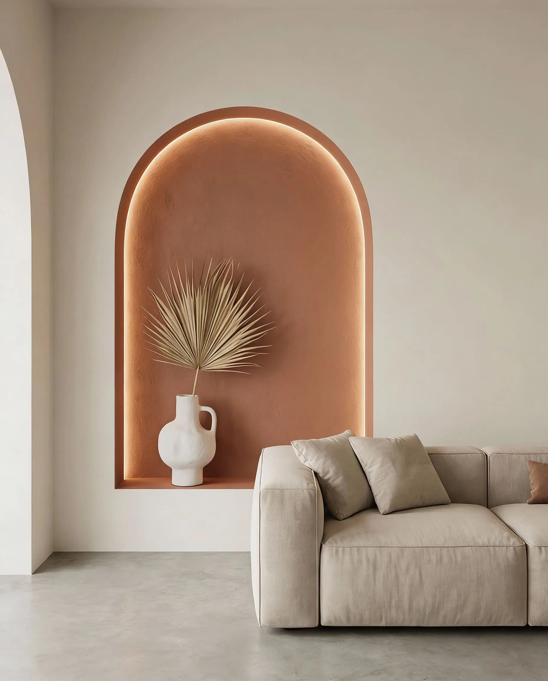 Minimalist living room featuring an arched wall niche painted in terracotta for an unexpected pop of color.