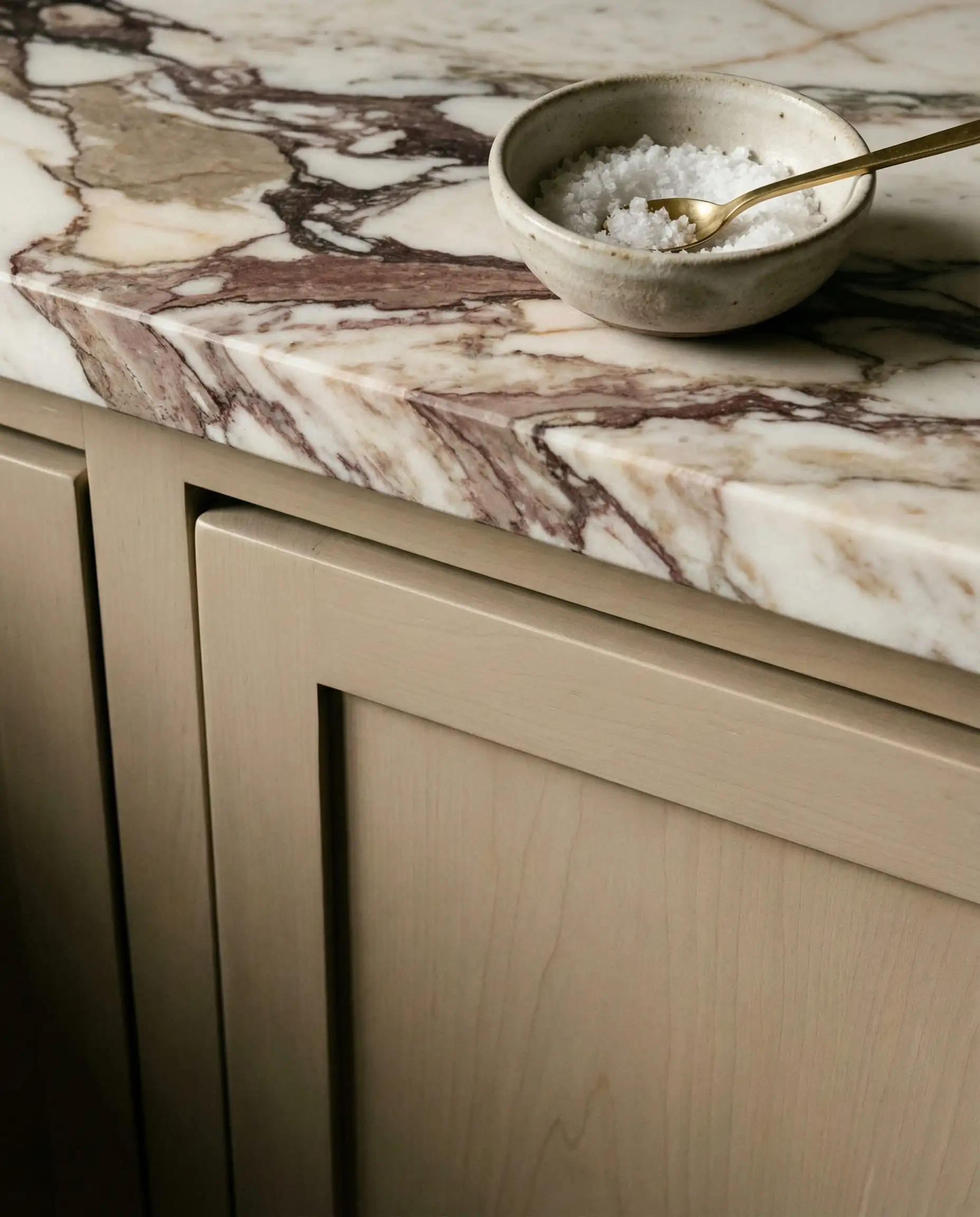Close up detail of Sherwin-Williams Universal Khaki cabinet door with Satin finish paired with Calacatta Viola marble countertop.