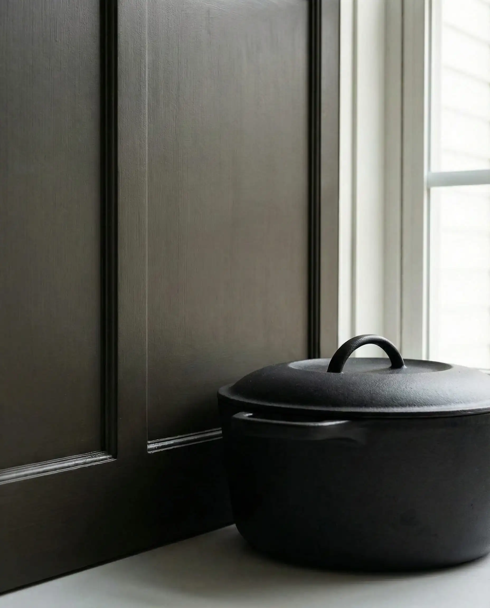 Close up of Sherwin-Williams Urbane Bronze cabinet next to a black pot showing brown undertones.
