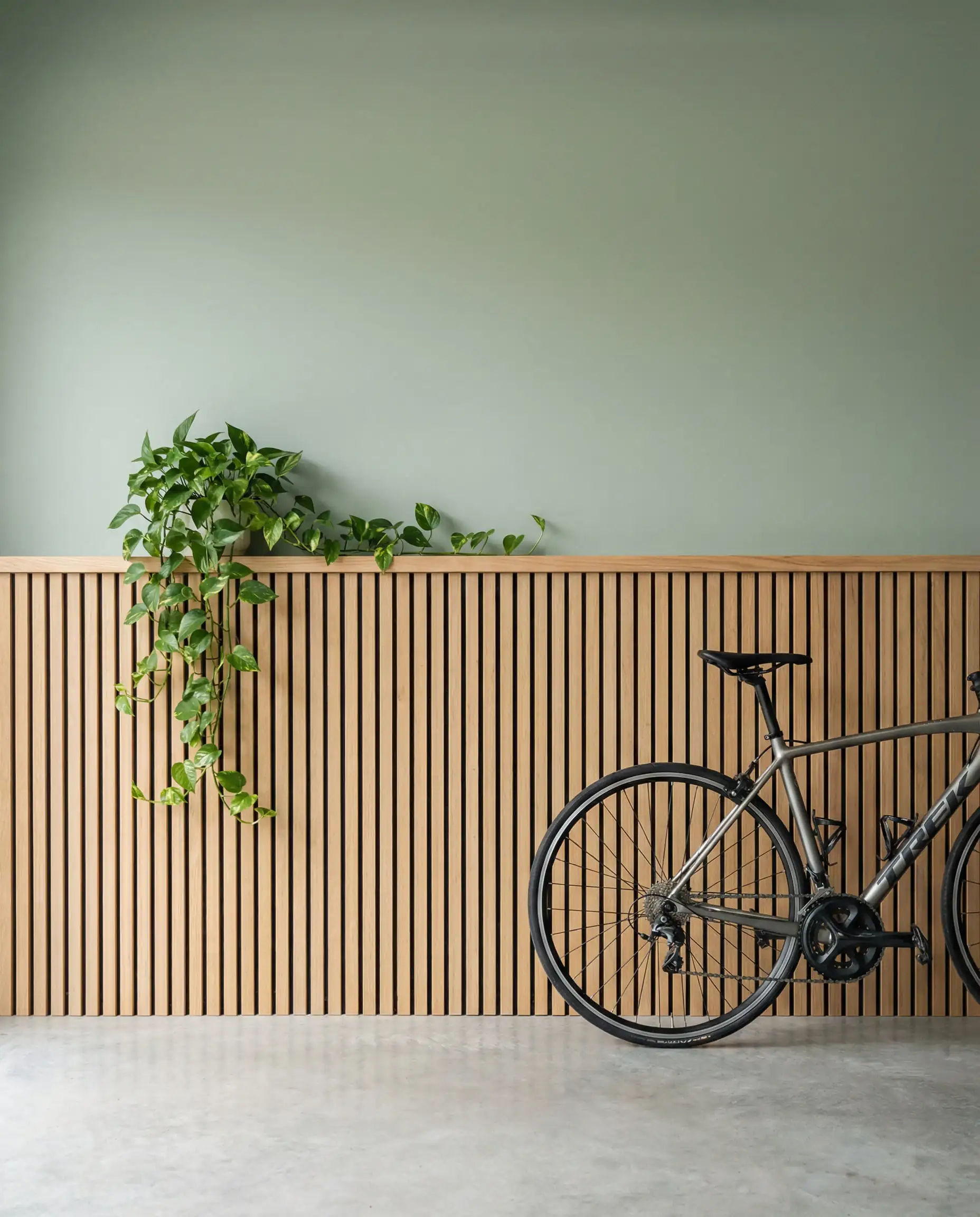 Garage wall featuring vertical white oak wood slat wainscoting on the bottom and sage green paint on top.