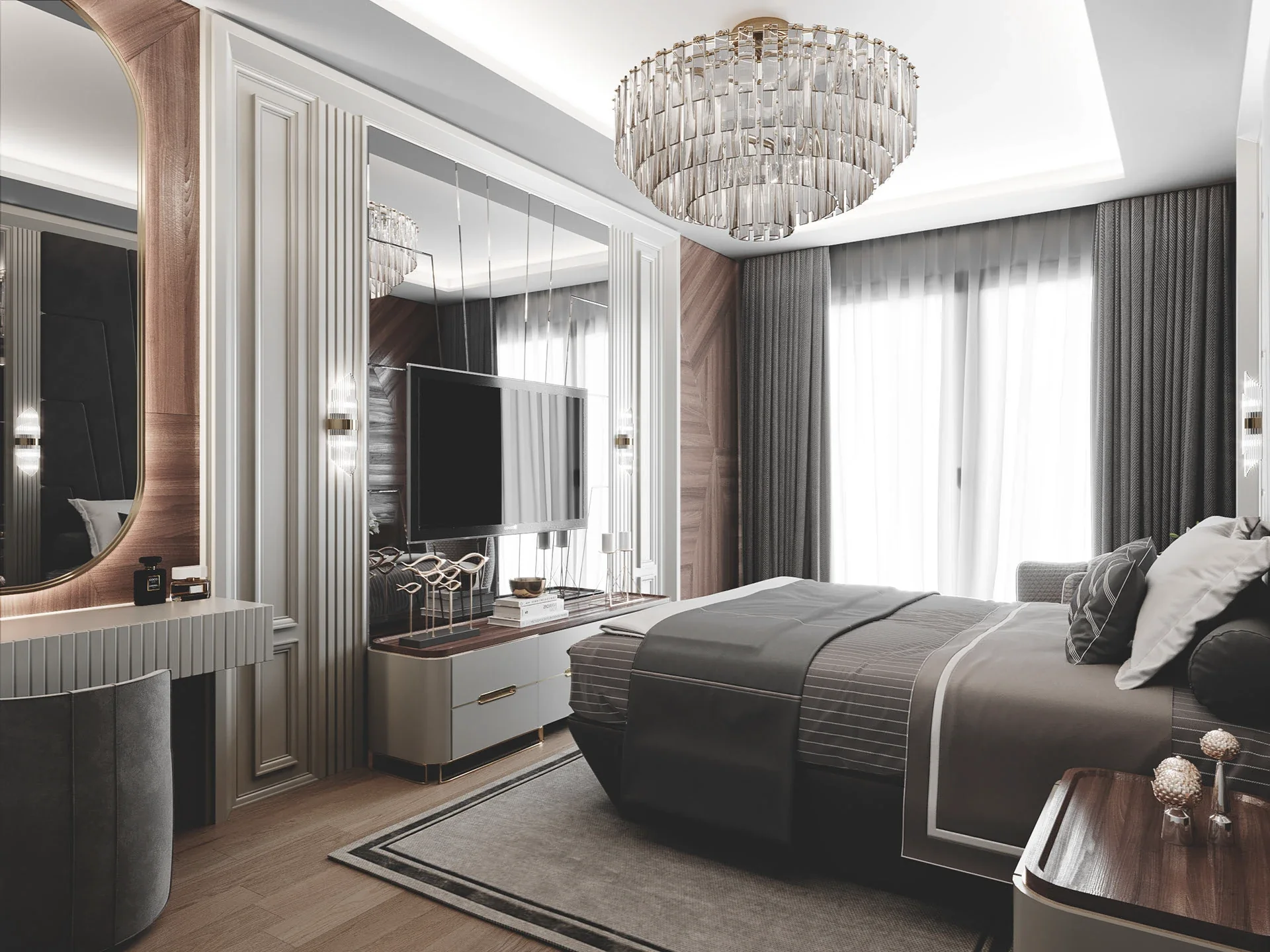 A luxurious bedroom featuring a tiered crystal chandelier, a dark grey bed, a mirrored accent wall behind a flat-screen TV, and a curved vanity desk with a large oval mirror.