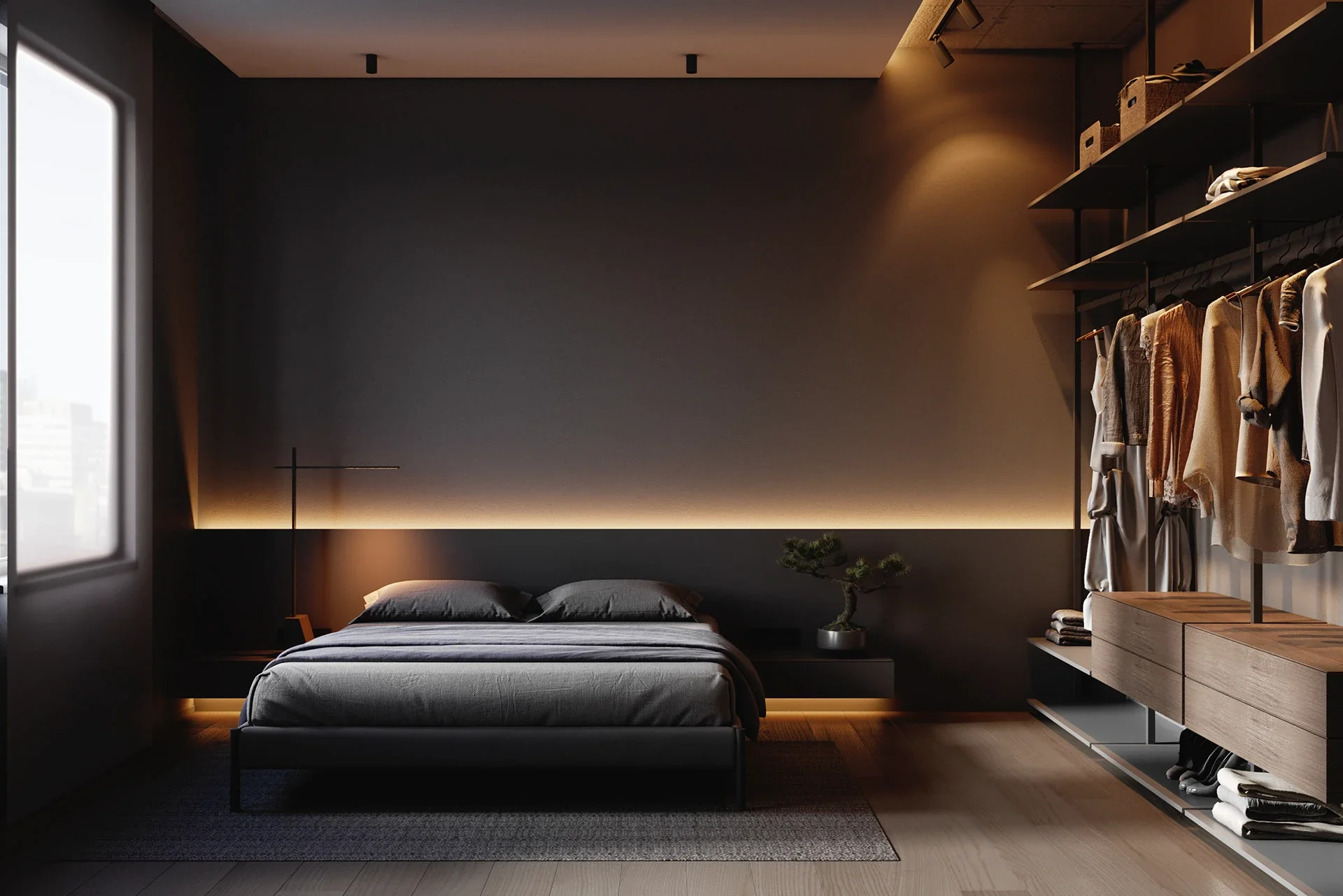 A moody, minimalist bedroom showcasing a low-profile dark bed against a dark grey wall with warm LED backlighting, adjacent to an open-concept wood and metal wardrobe system.