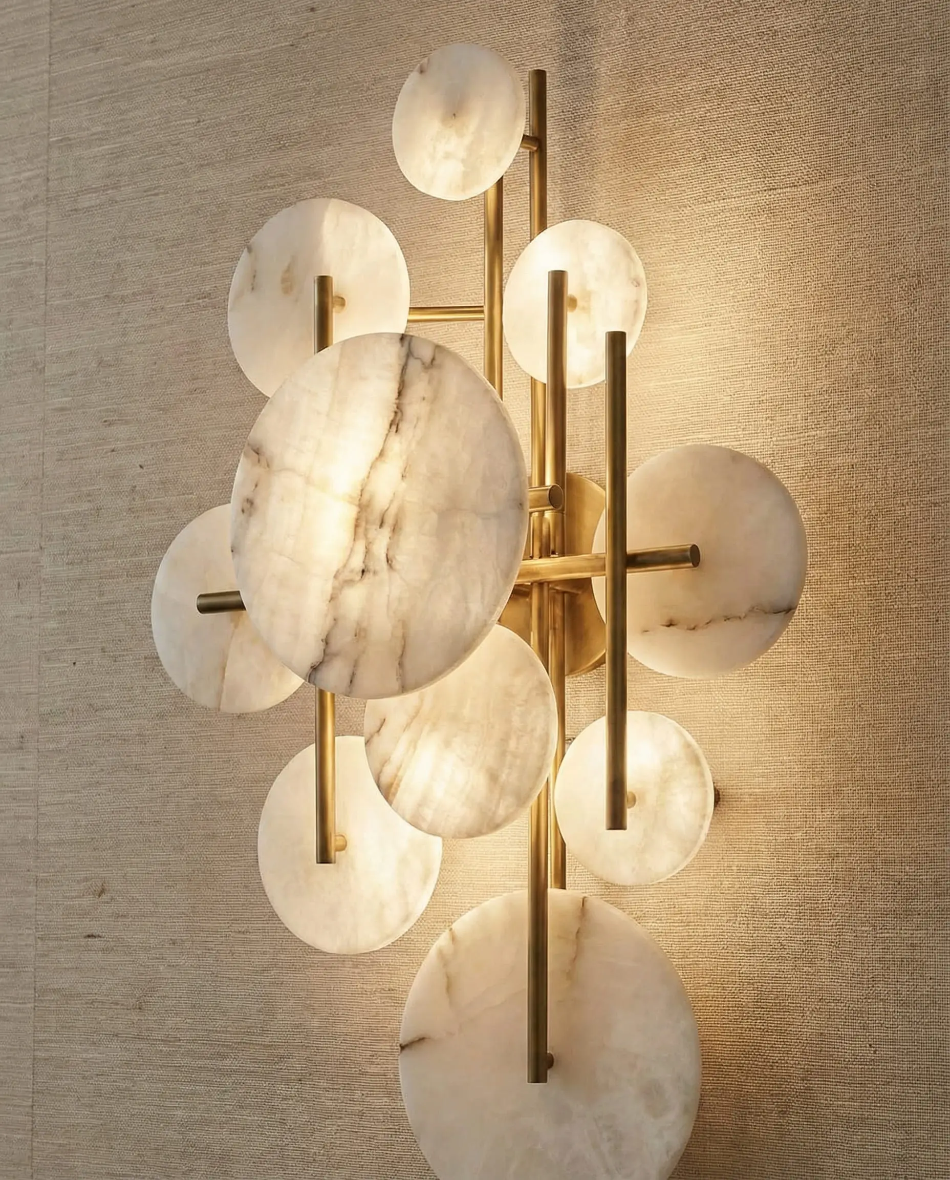 Close up of a luxury dining room wall featuring a geometric alabaster and brass wall light fixture.