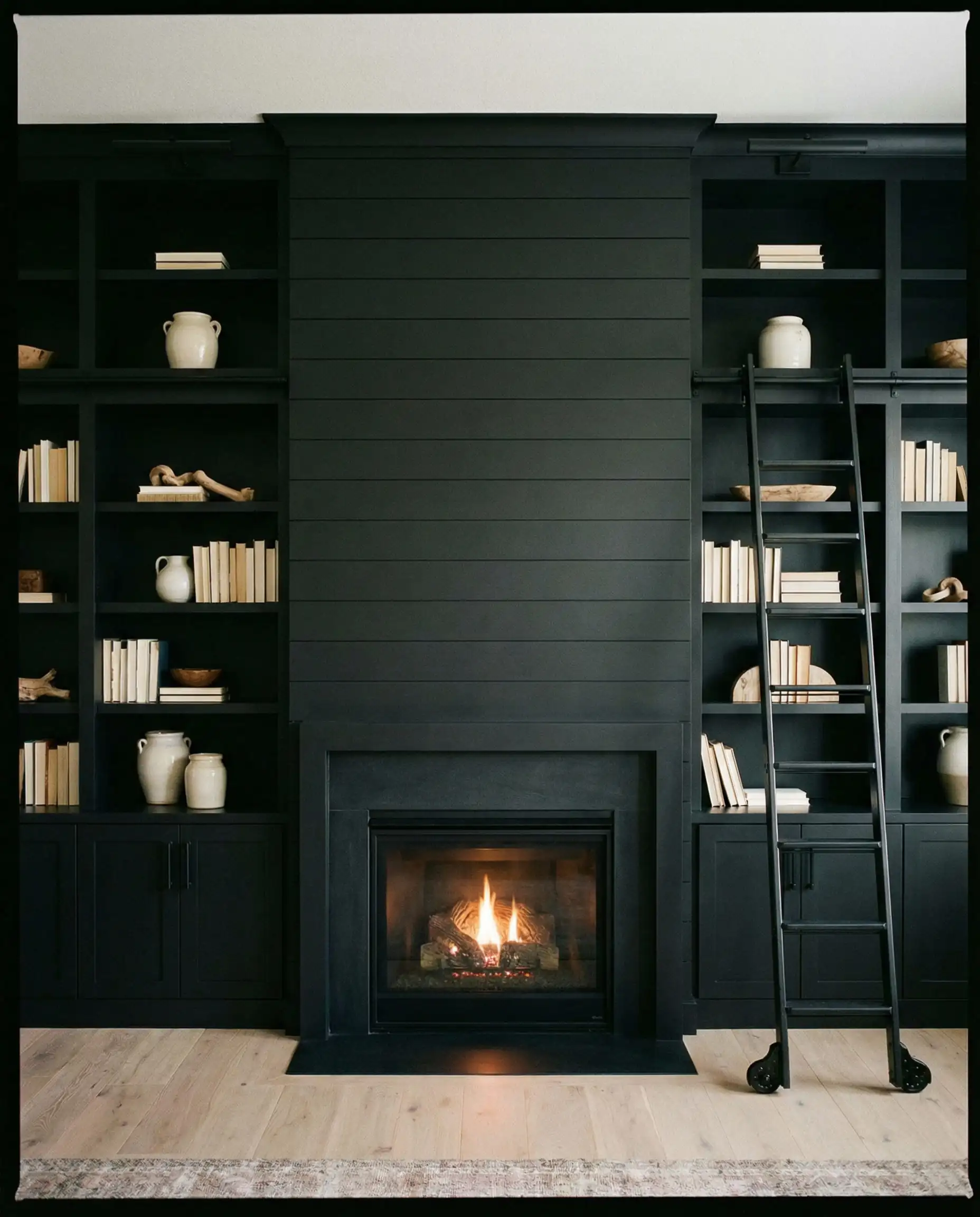 Symmetric black shiplap fireplace flanked by built-in bookshelves painted in matching Tricorn Black.