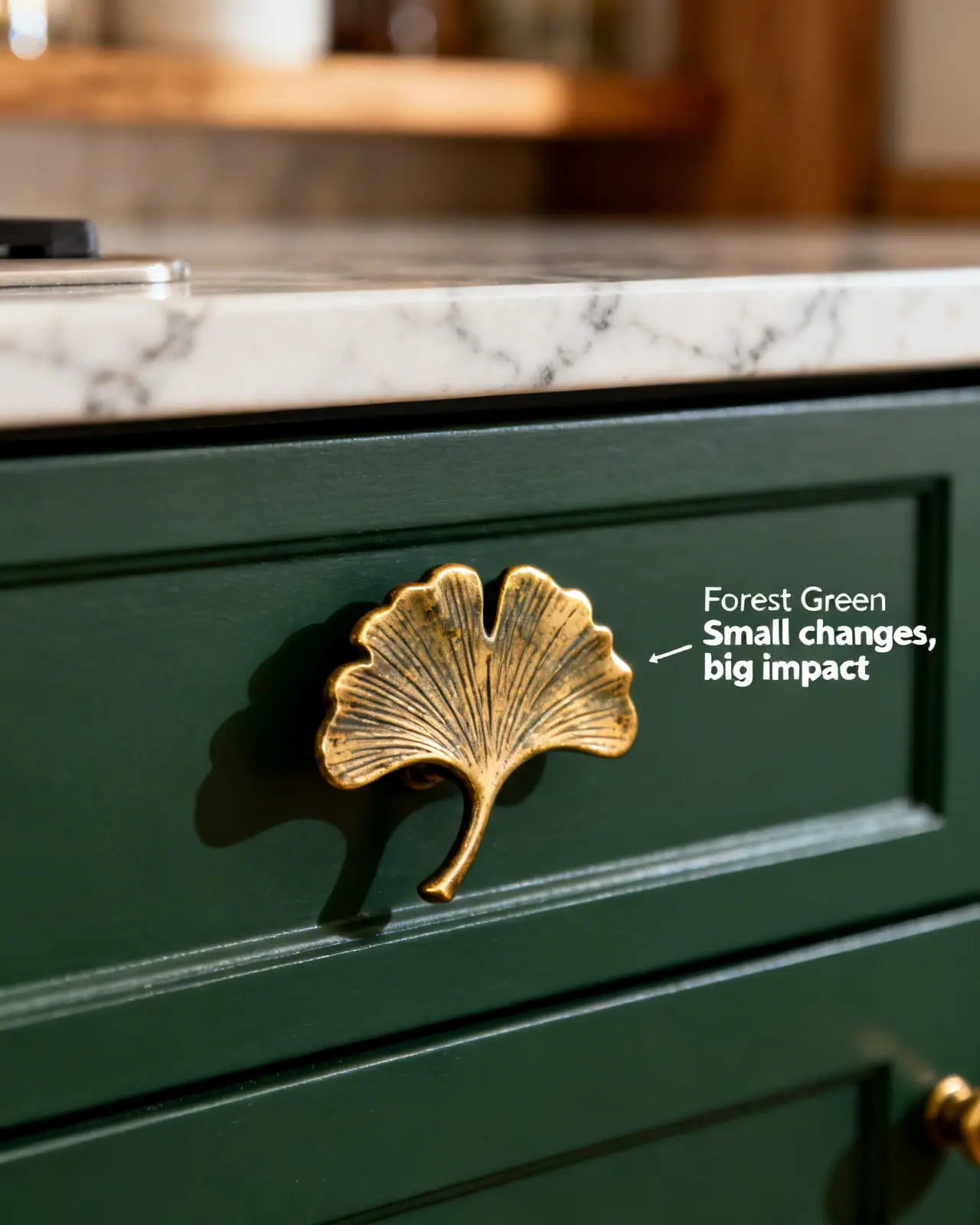 Close-up of a dark green kitchen drawer featuring an antique brass handle shaped like a ginkgo leaf.