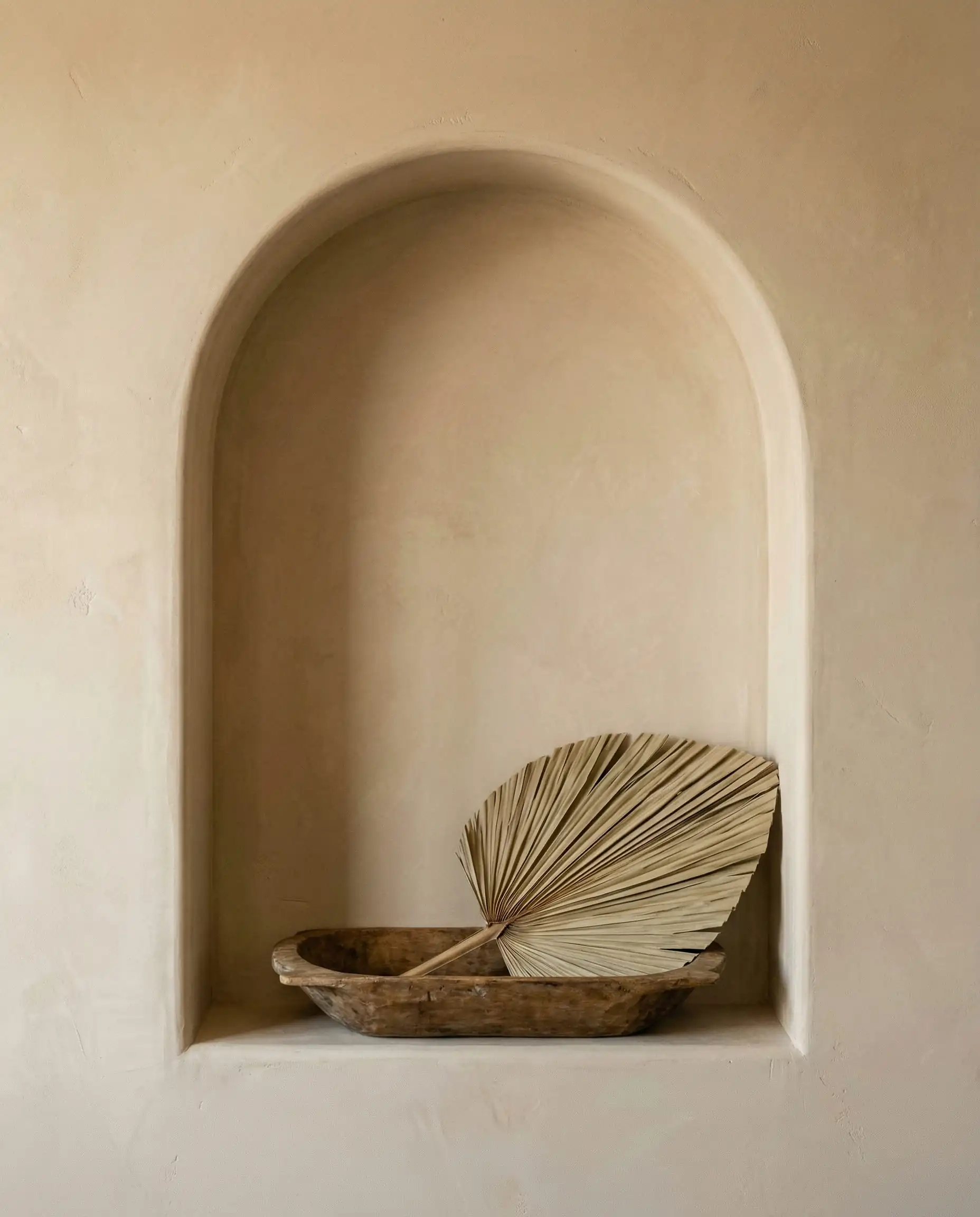 Close up of a textured drywall alcove with an arched top and minimalist styling in a living room.