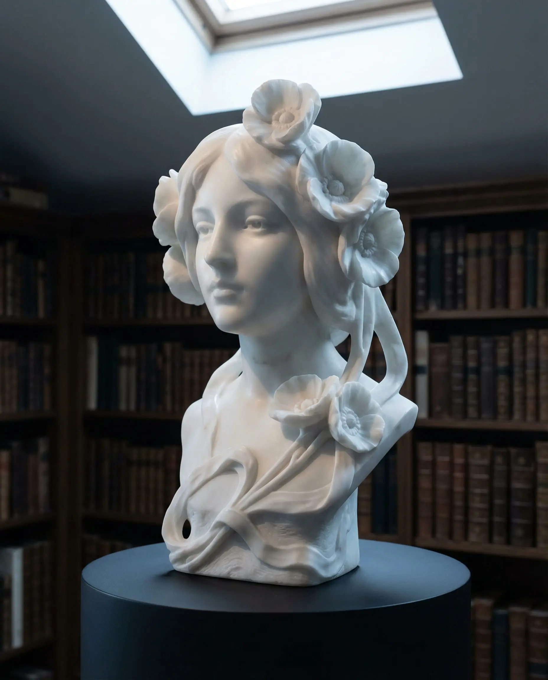 White marble bust sculpture of a woman with flowing hair merging into flowers, styled in a moody modern home library.