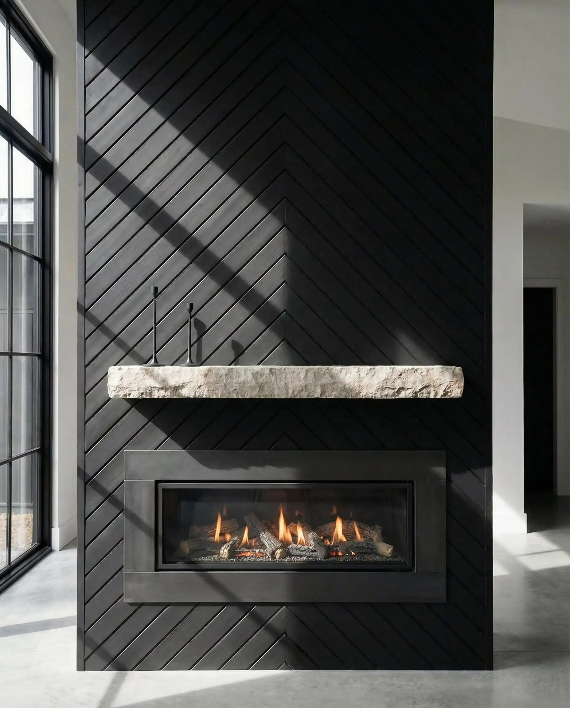 Dramatic feature wall with matte black wood shiplap installed in a precise chevron pattern.