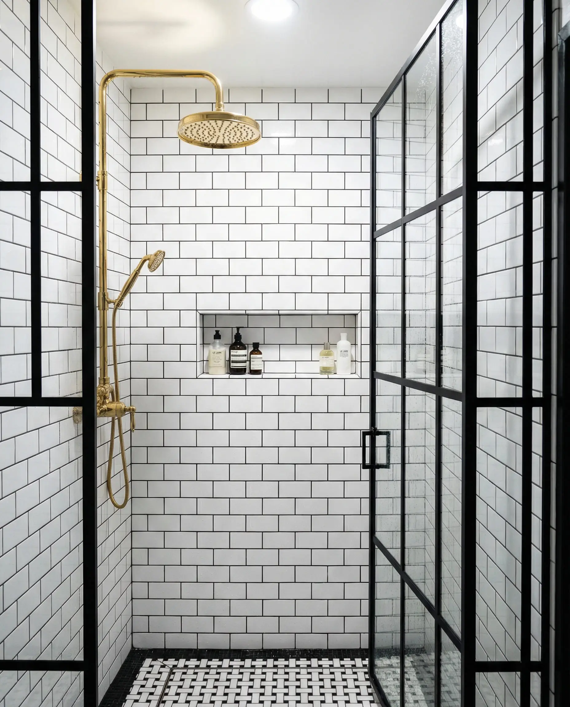 Walk-in shower with black grid glass doors and polished gold rain shower head.