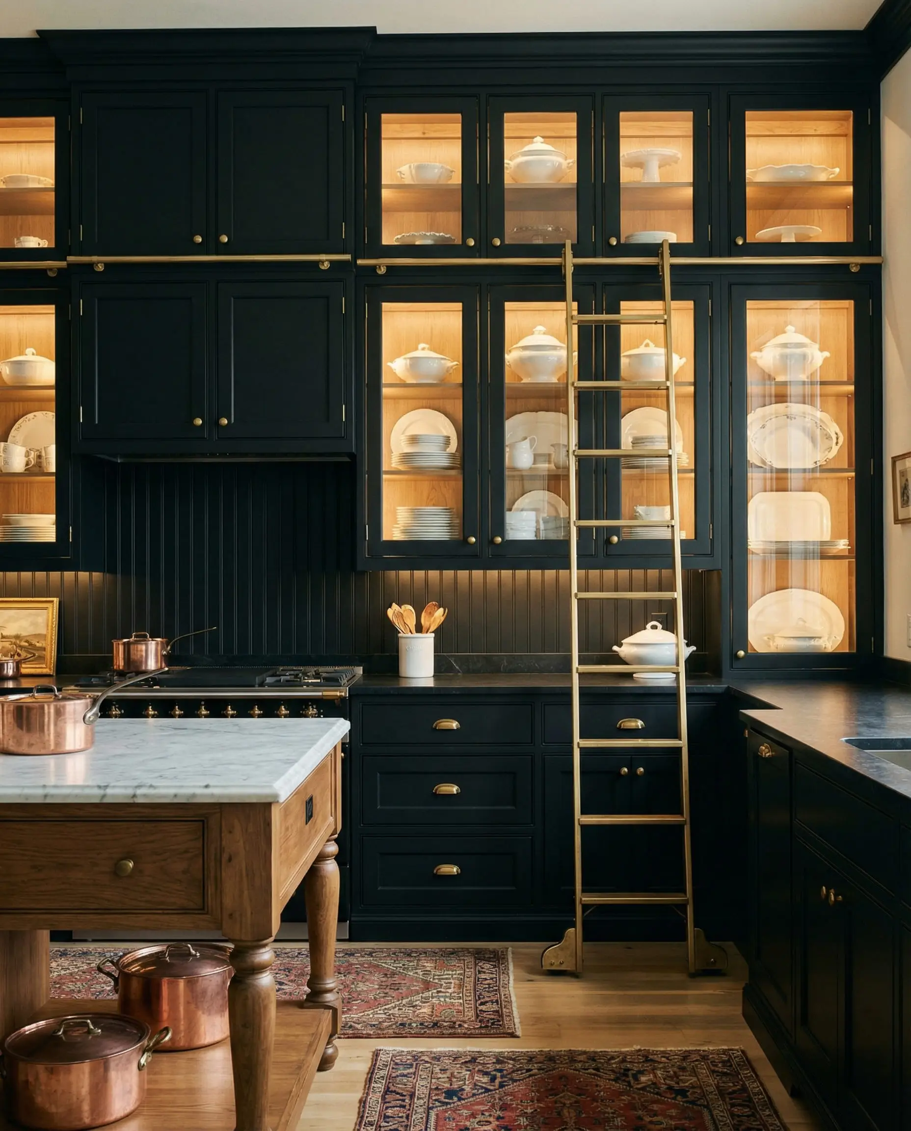 Floor-to-ceiling black kitchen cabinets featuring a gold rolling library ladder.