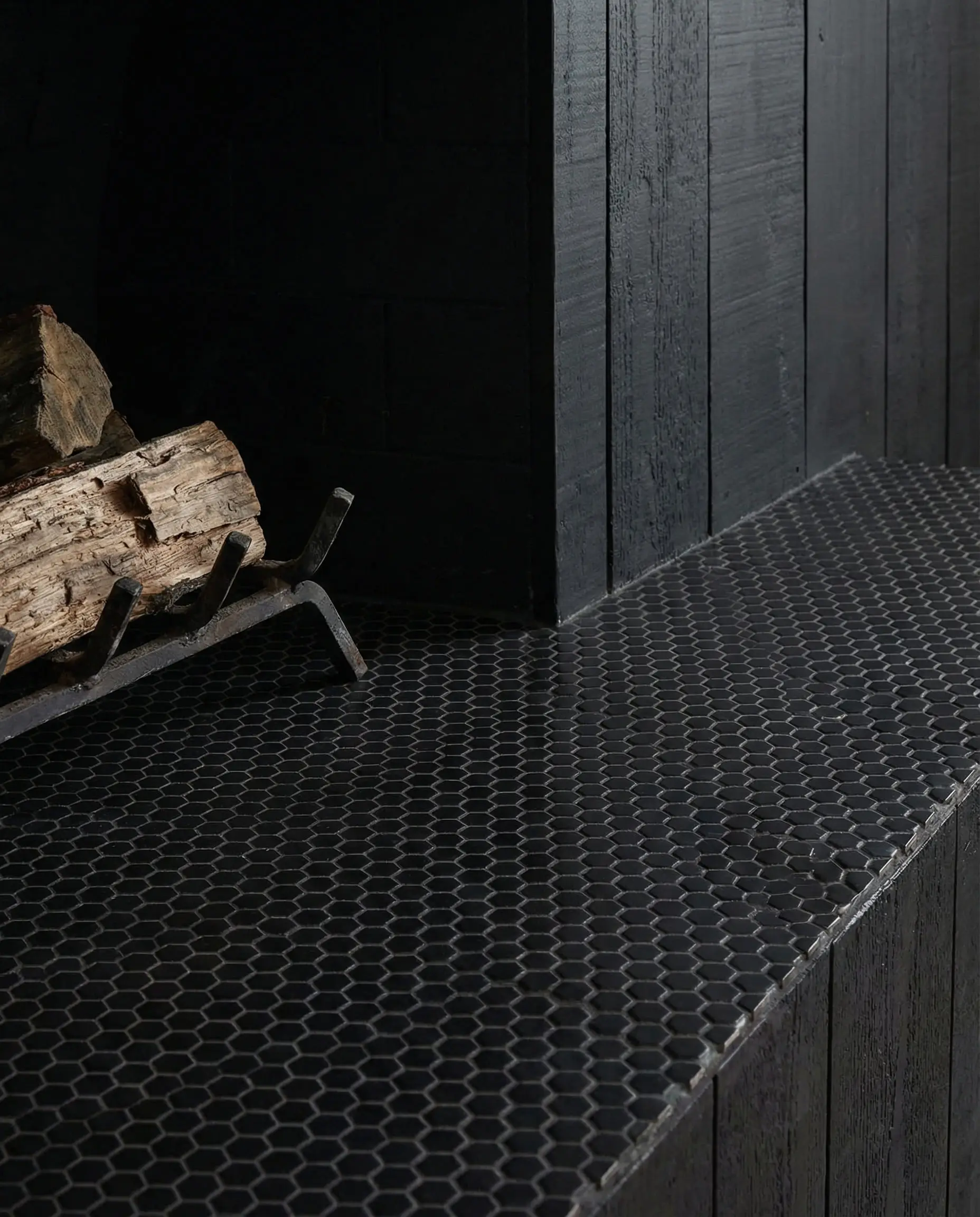Matte black hexagon mosaic tile hearth with vintage rug layered over it.