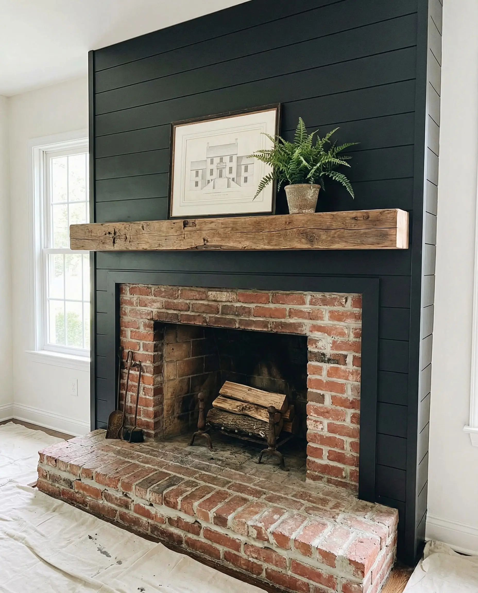 Transitional fireplace with new black shiplap on top and original red brick hearth on the bottom.