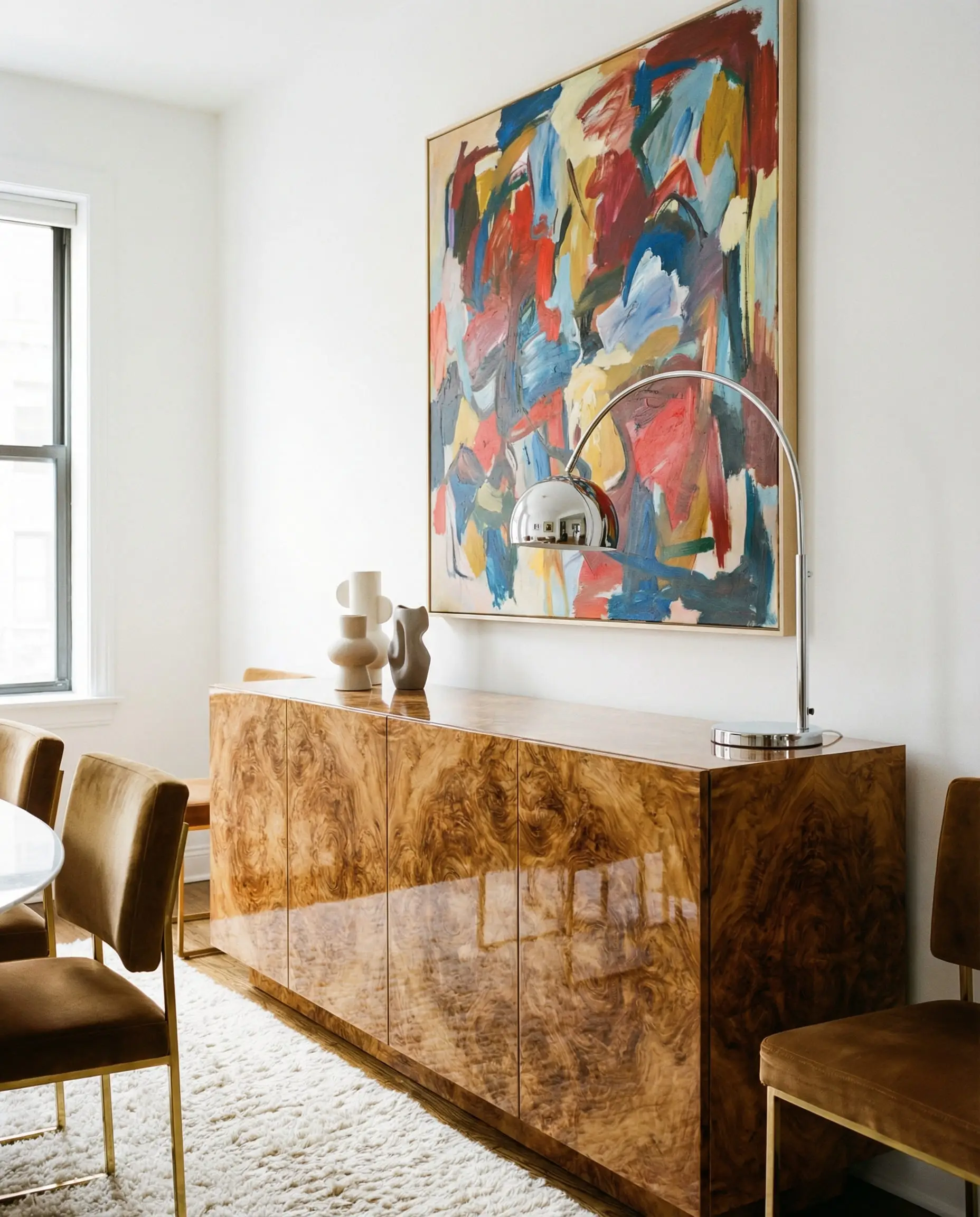 High-gloss burl wood sideboard with abstract art on a white wall in a modern living room.