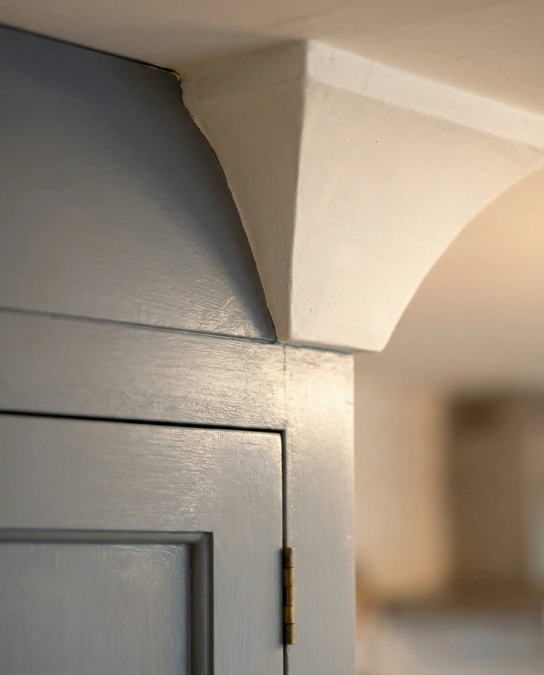 Macro detail showing the temperature difference between cool gray cabinet molding and warm milky white wall paint.