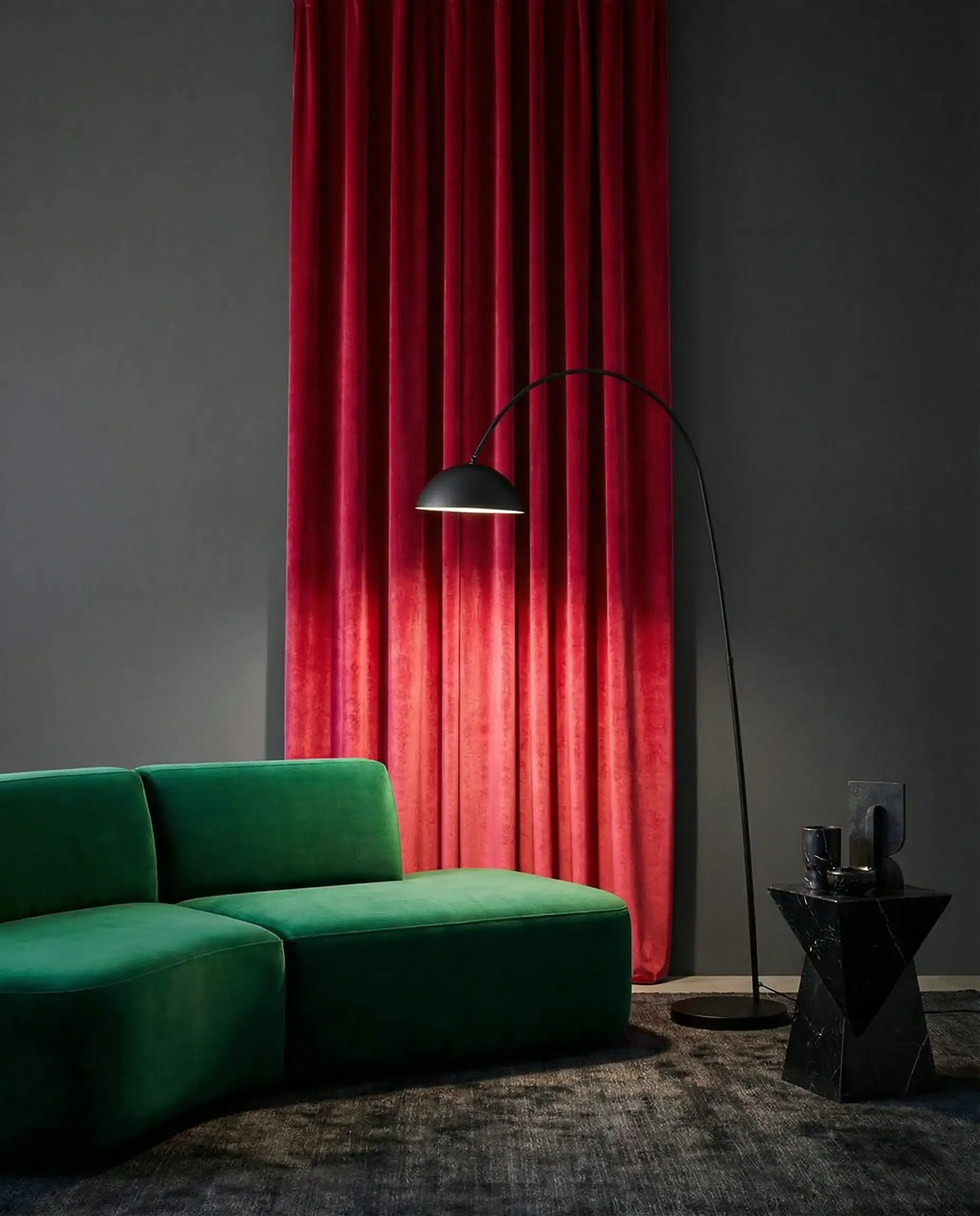 High-contrast interior design featuring vibrant red velvet curtains against a matte charcoal grey wall.