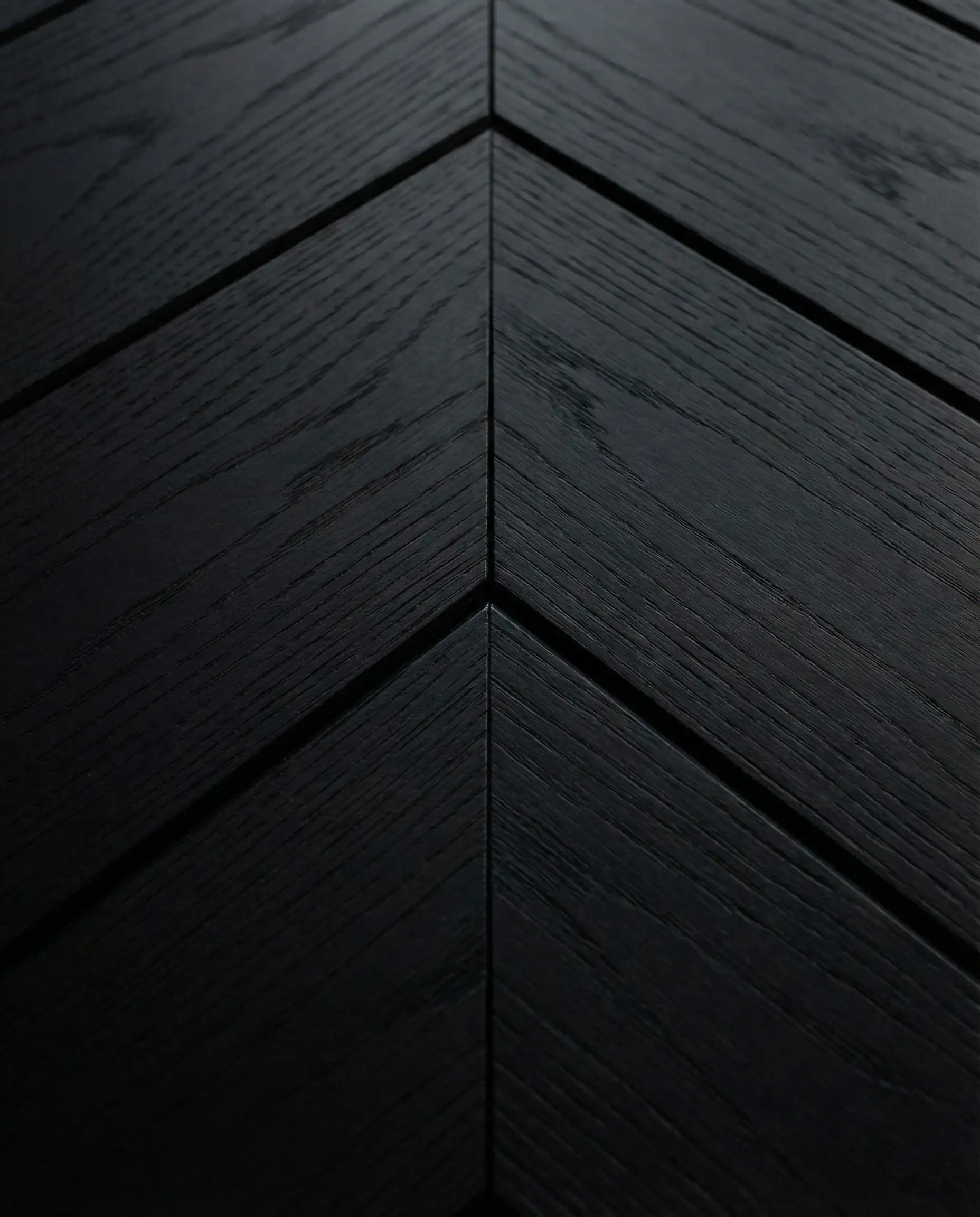 Macro detail shot of the center mitered joint on a black chevron shiplap fireplace installation.
