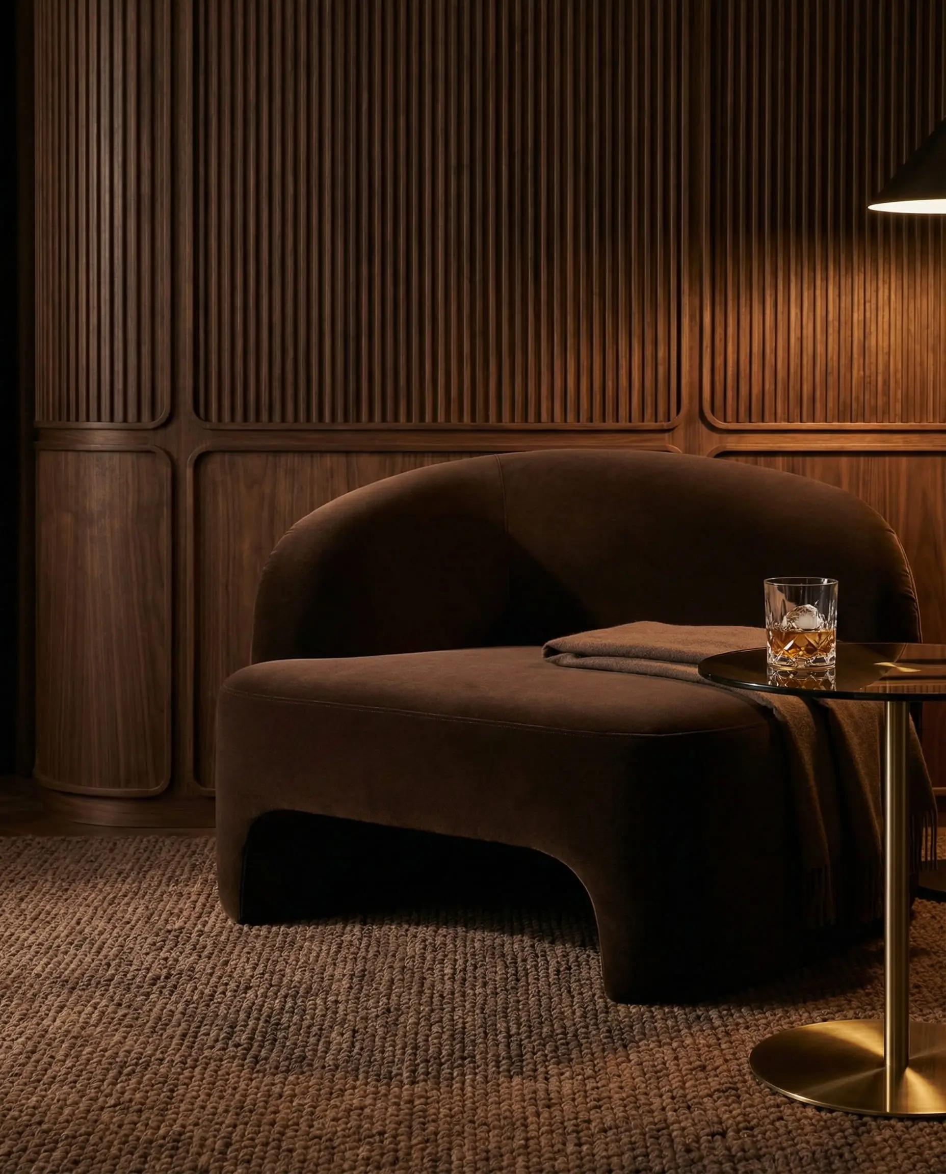 Cozy reading corner featuring a chocolate brown velvet armchair set against dark walnut wood paneling.