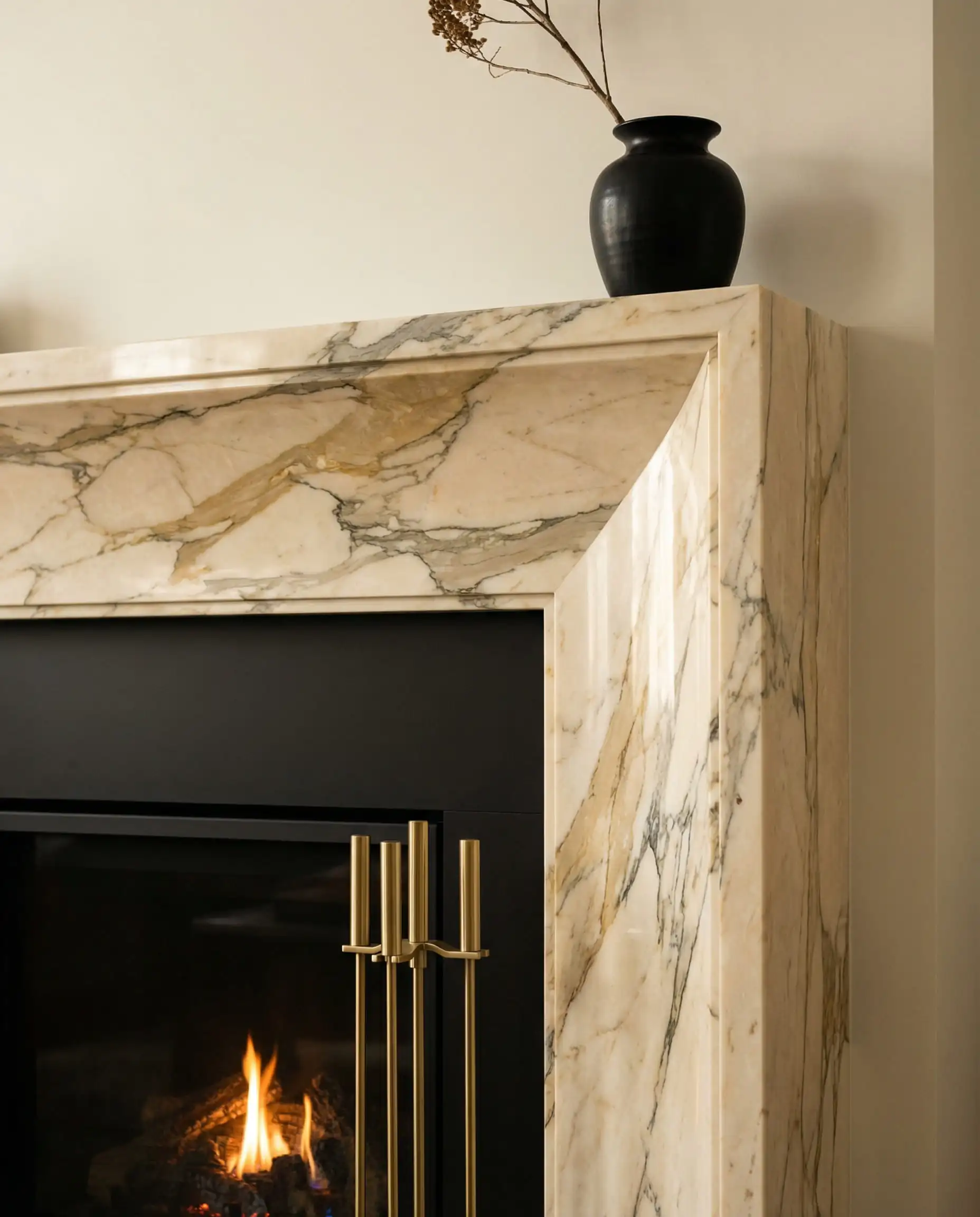 Close-up of a cream marble fireplace mantel with gold veining and a matte black firebox.