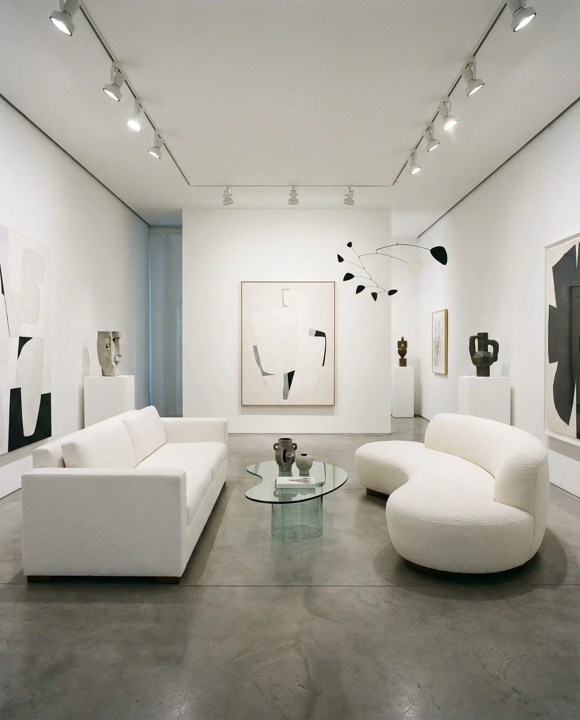 A modern white living room featuring a straight rectangular linen sofa facing a curved bouclé sofa in the same white color.