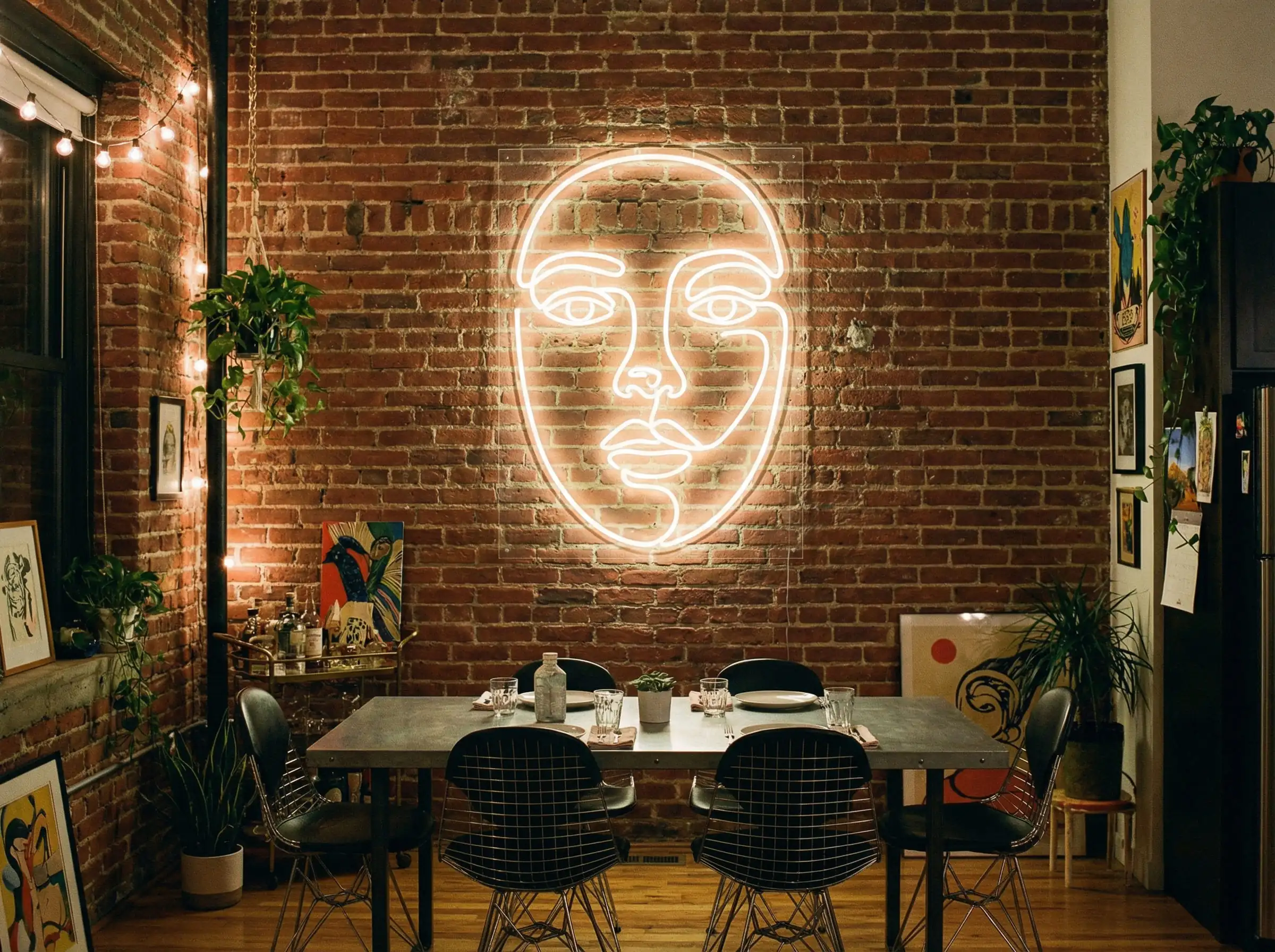 Industrial loft dining space featuring a warm white custom neon sign mounted on an exposed red brick wall.