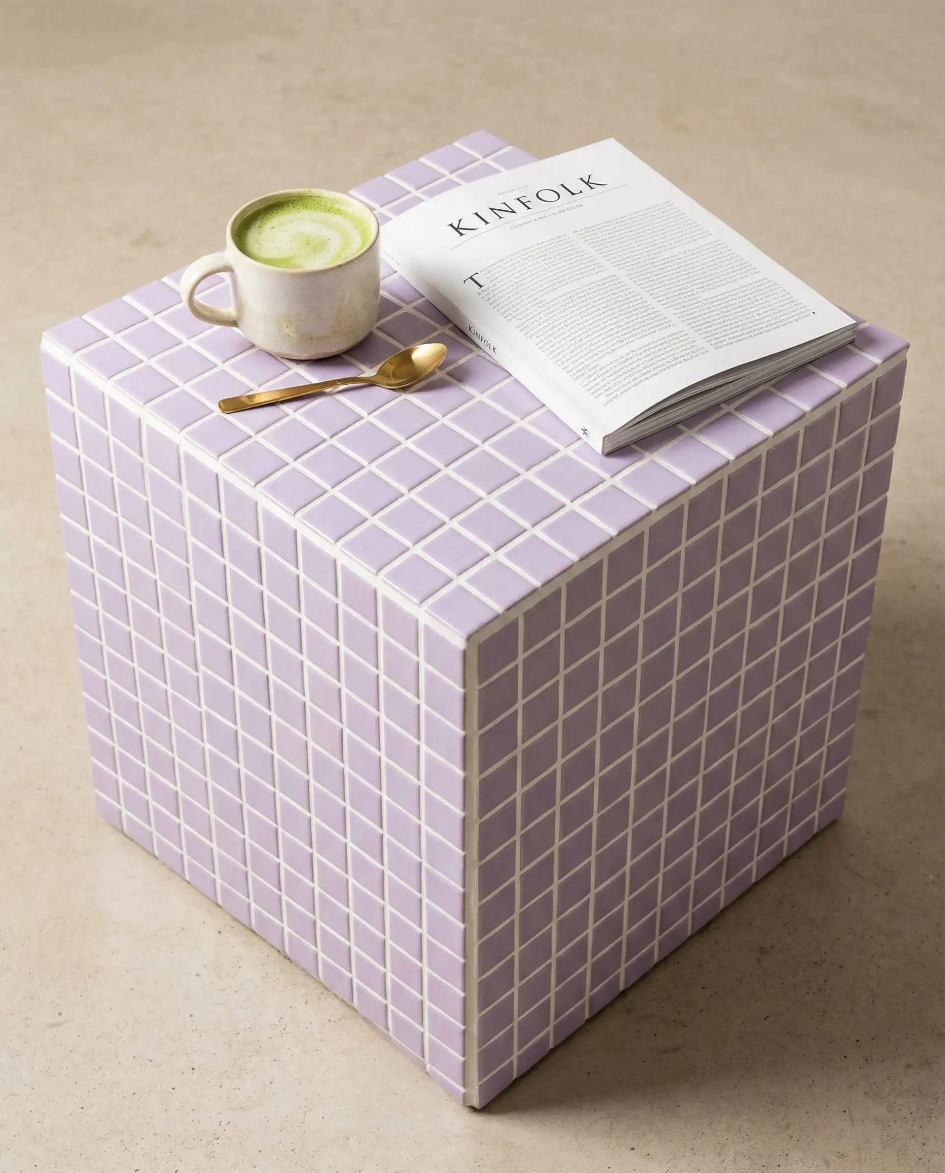 Pastel lilac tiled cube side table with white grout styled with coffee and magazines for a grid aesthetic.