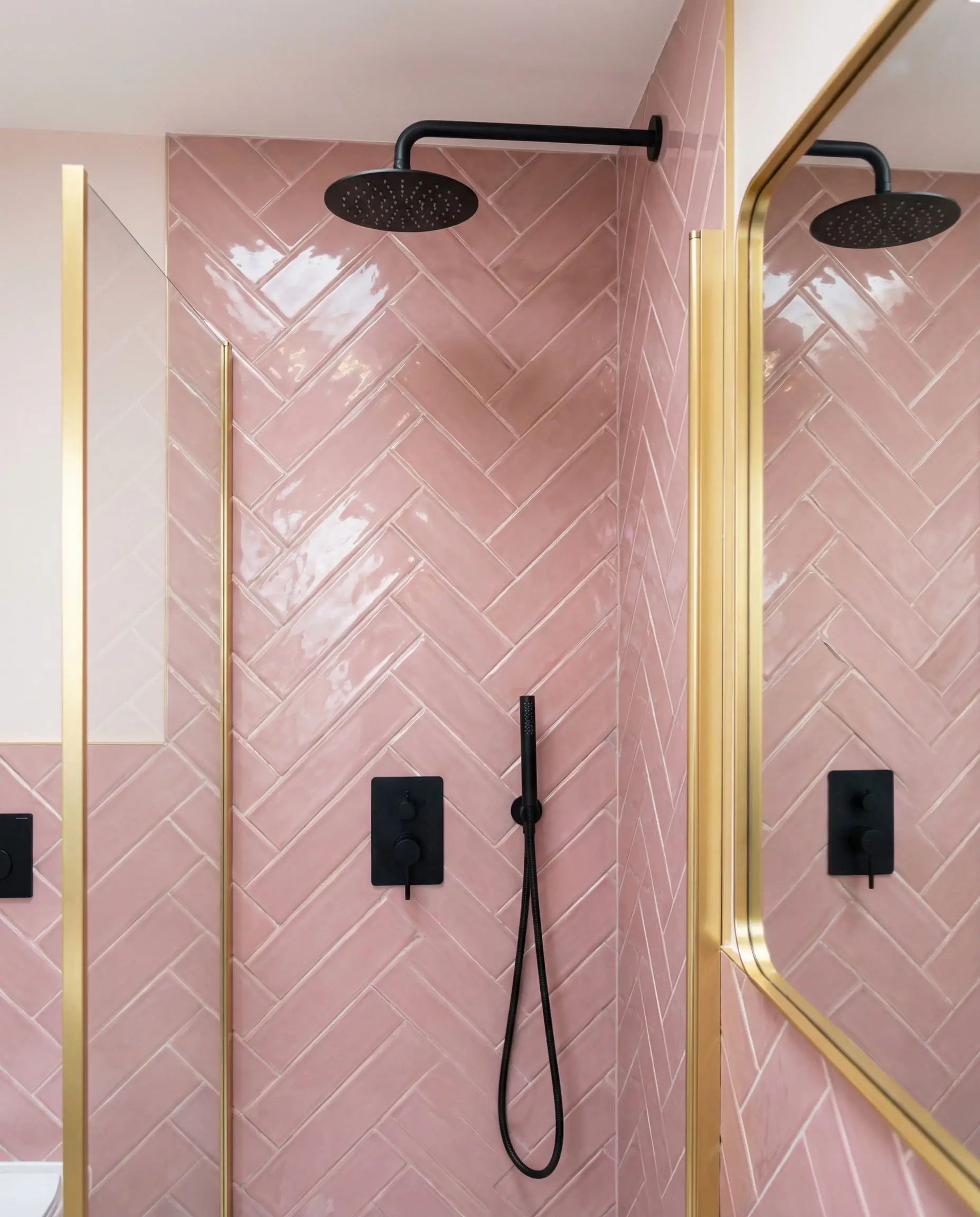 Modern bathroom shower featuring dusty pink herringbone tiles and matte black fixtures.