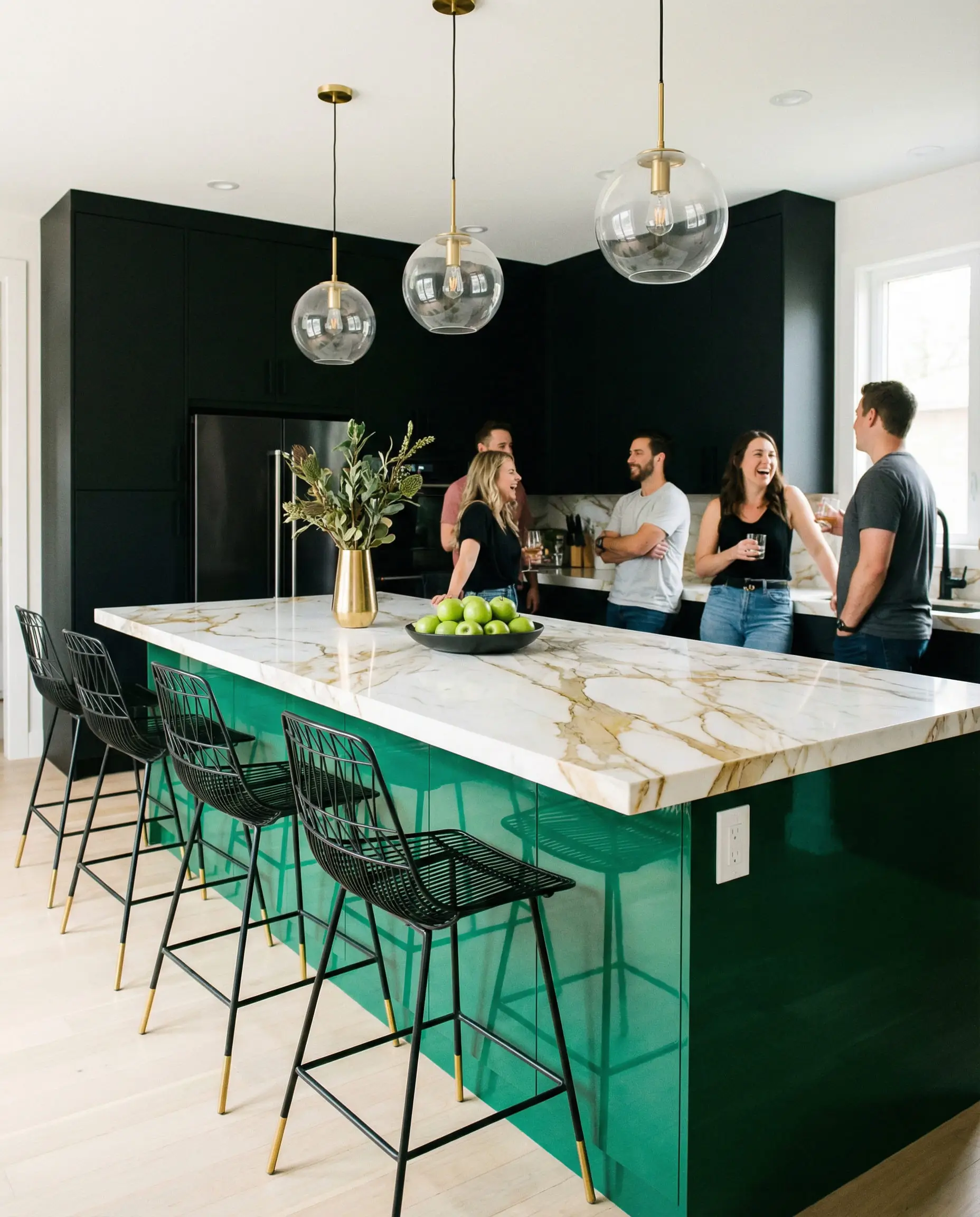 Modern kitchen featuring a bold emerald green island with white marble and black cabinetry.