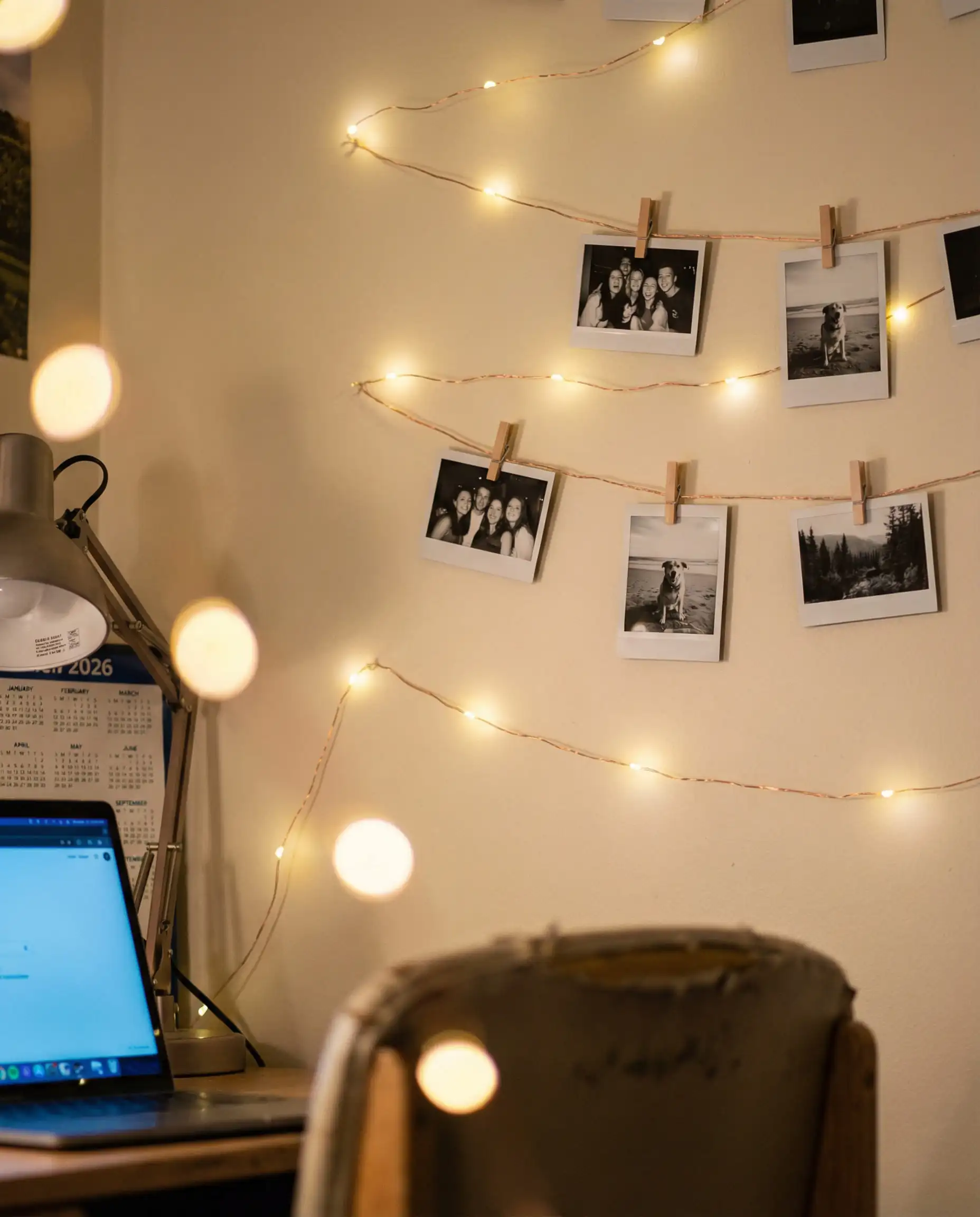 Aesthetic photo wall display with polaroid pictures clipped to copper string lights.