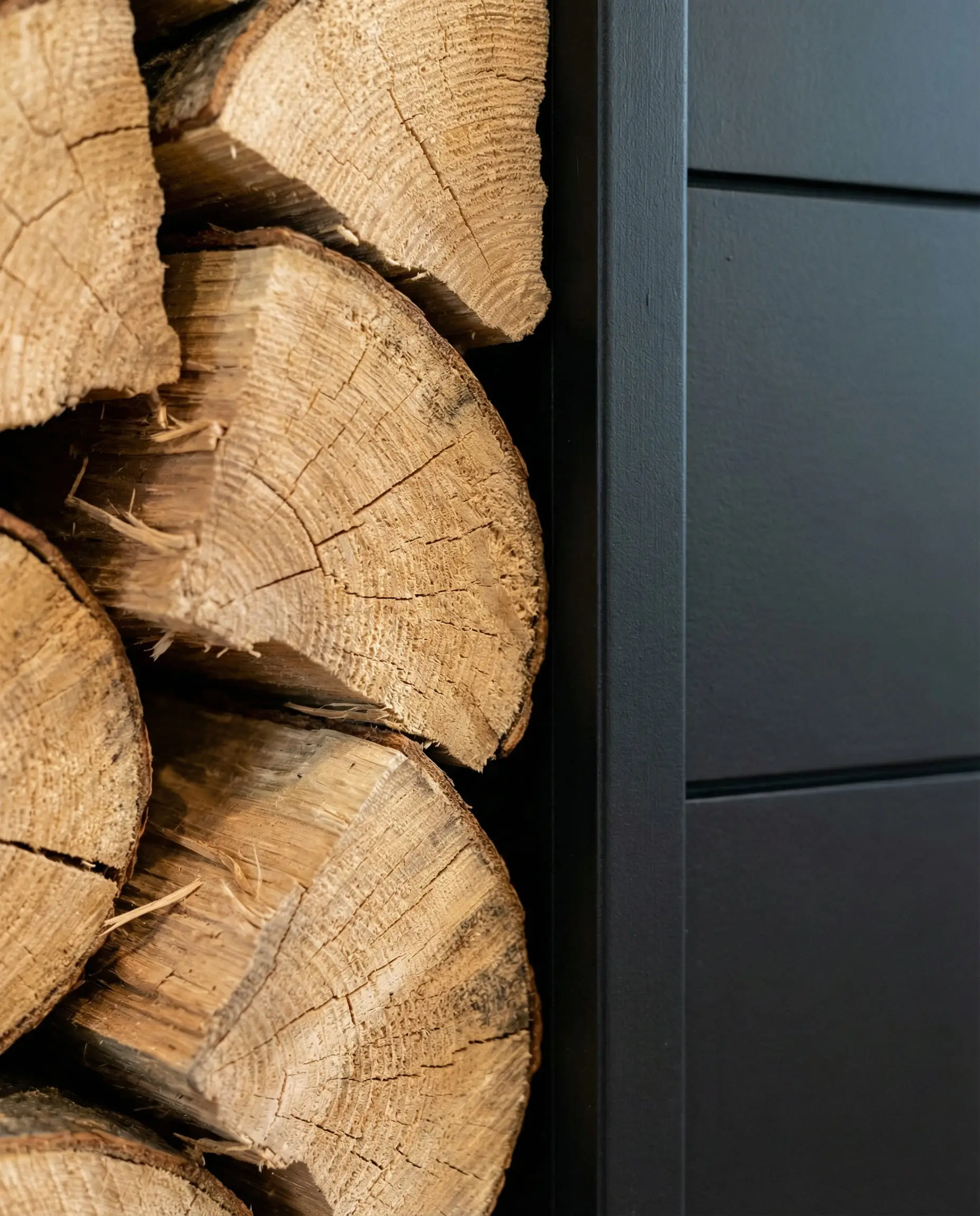 Close-up texture shot of raw firewood log ends against smooth black paint.