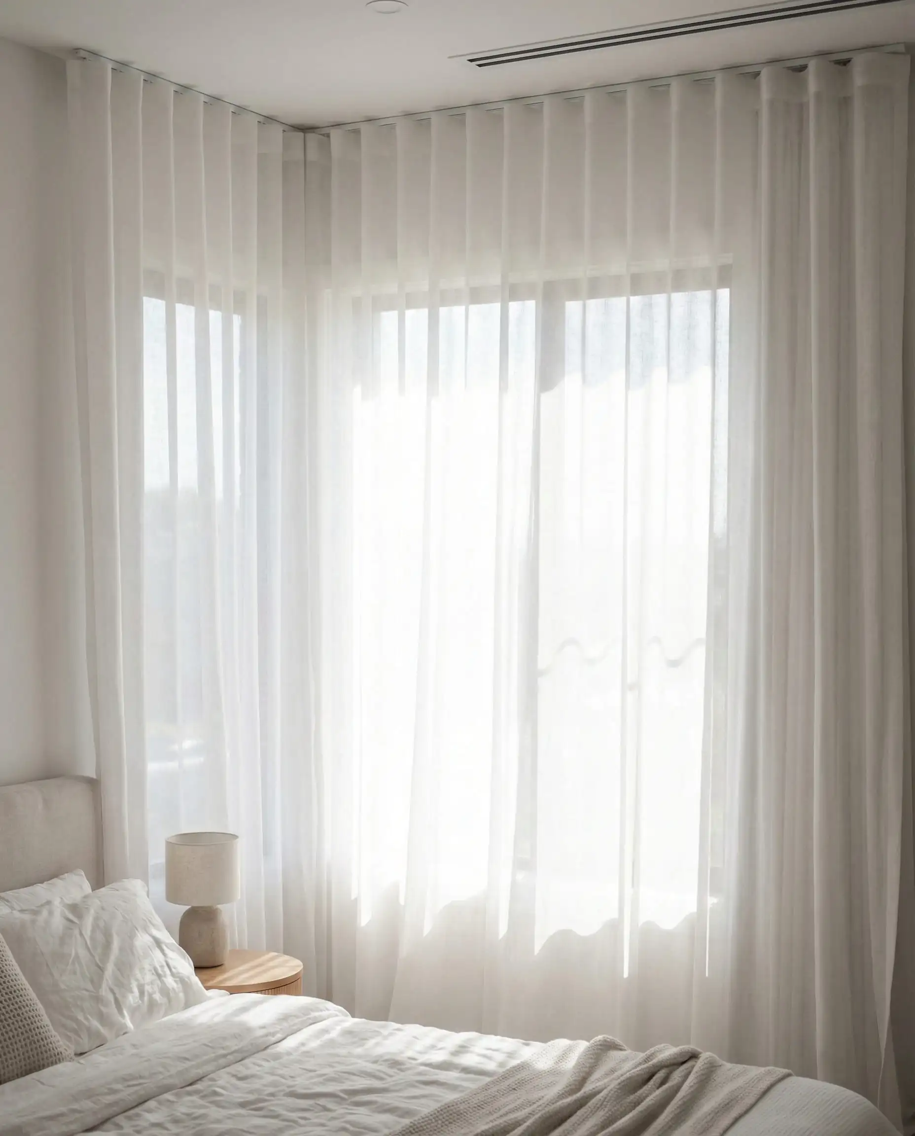 Sheer white curtains hung from ceiling to floor to make a small window look larger.