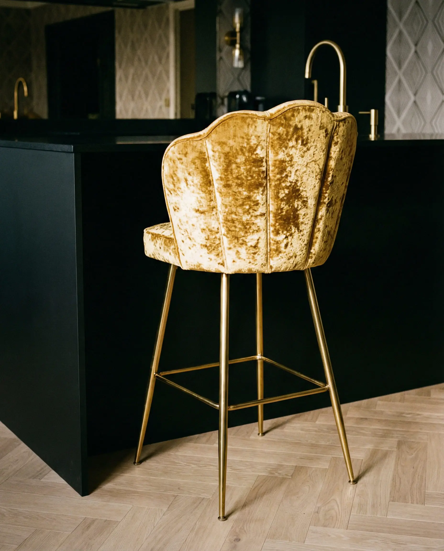 Black kitchen island featuring an Art Deco gold velvet bar stool with brass legs.