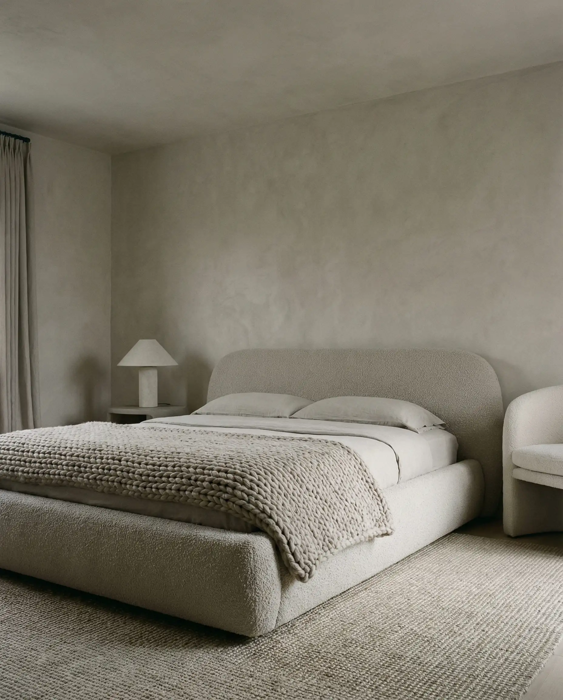 Monochromatic greige bedroom with textured boucle bed and lime wash walls.