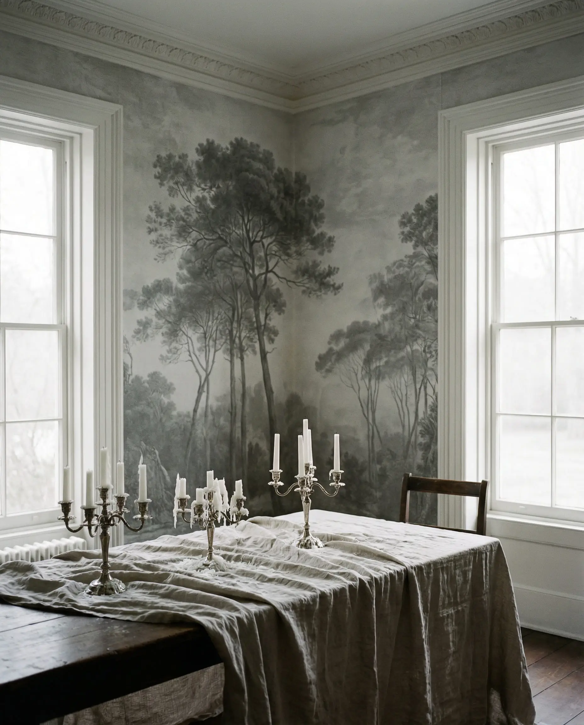 Moody dining room featuring a floor-to-ceiling vintage etching-style mural of a misty pine forest in grey and white.