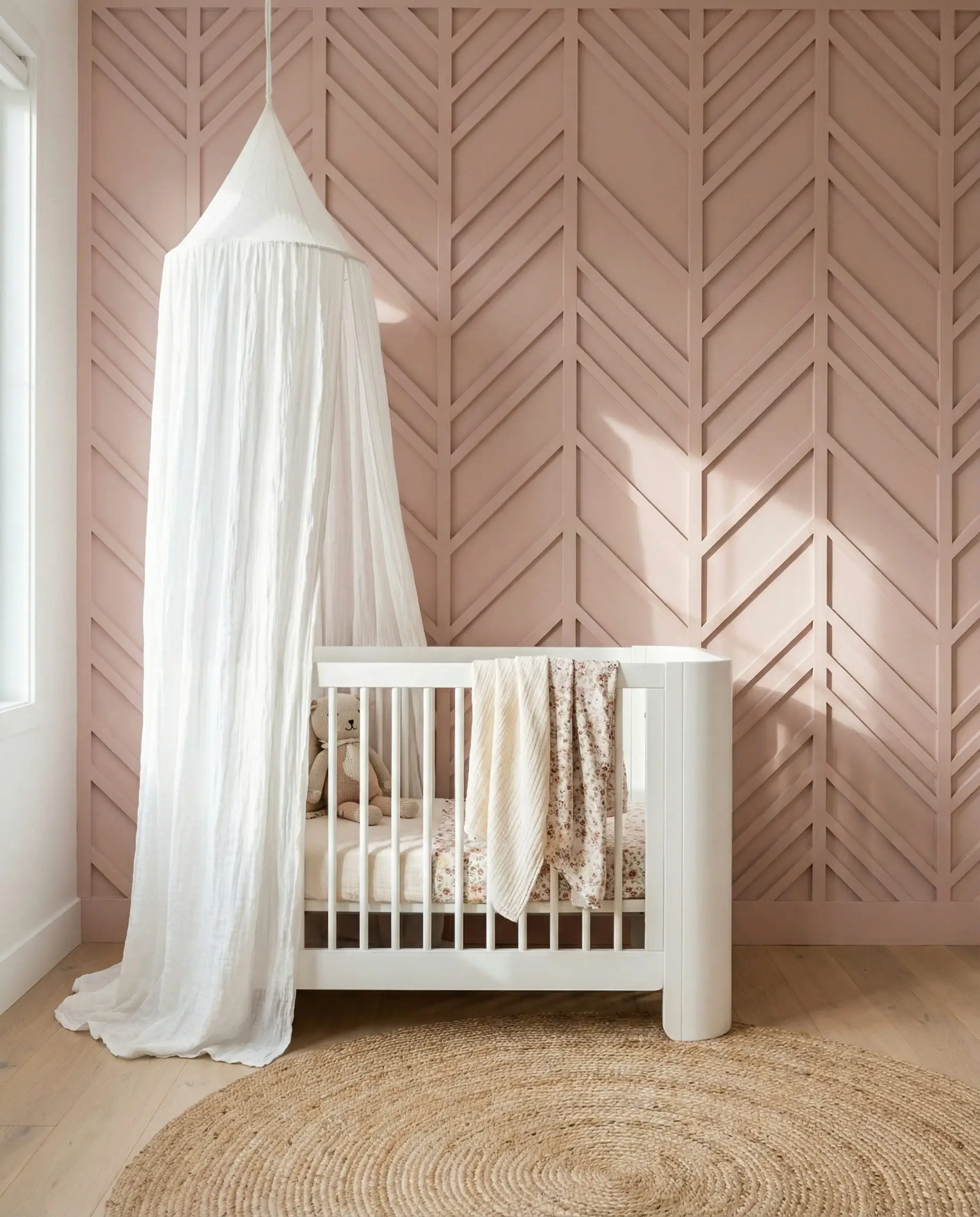 Blush pink nursery wall featuring intricate herringbone board and batten pattern with modern white crib.