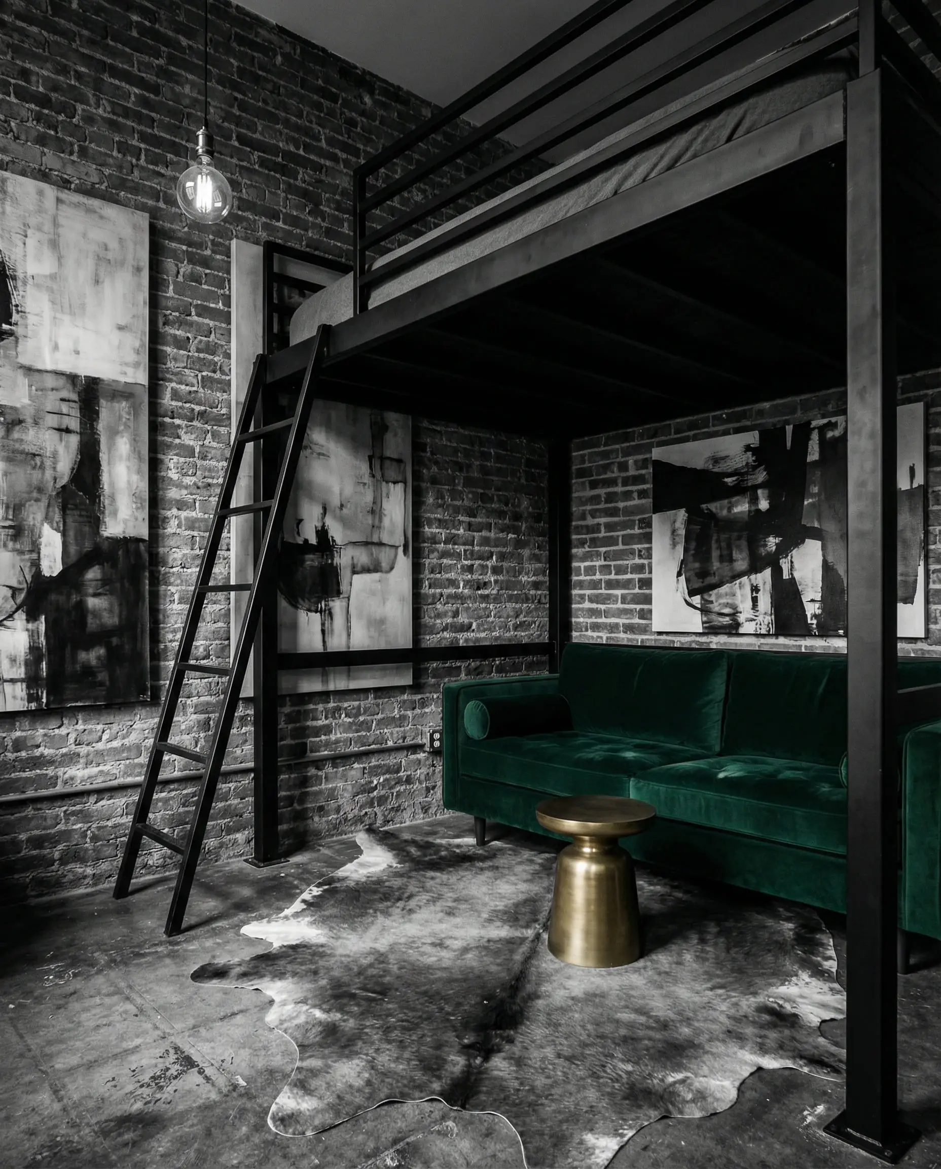Industrial style matte black metal loft bed with velvet sofa underneath against a brick wall.