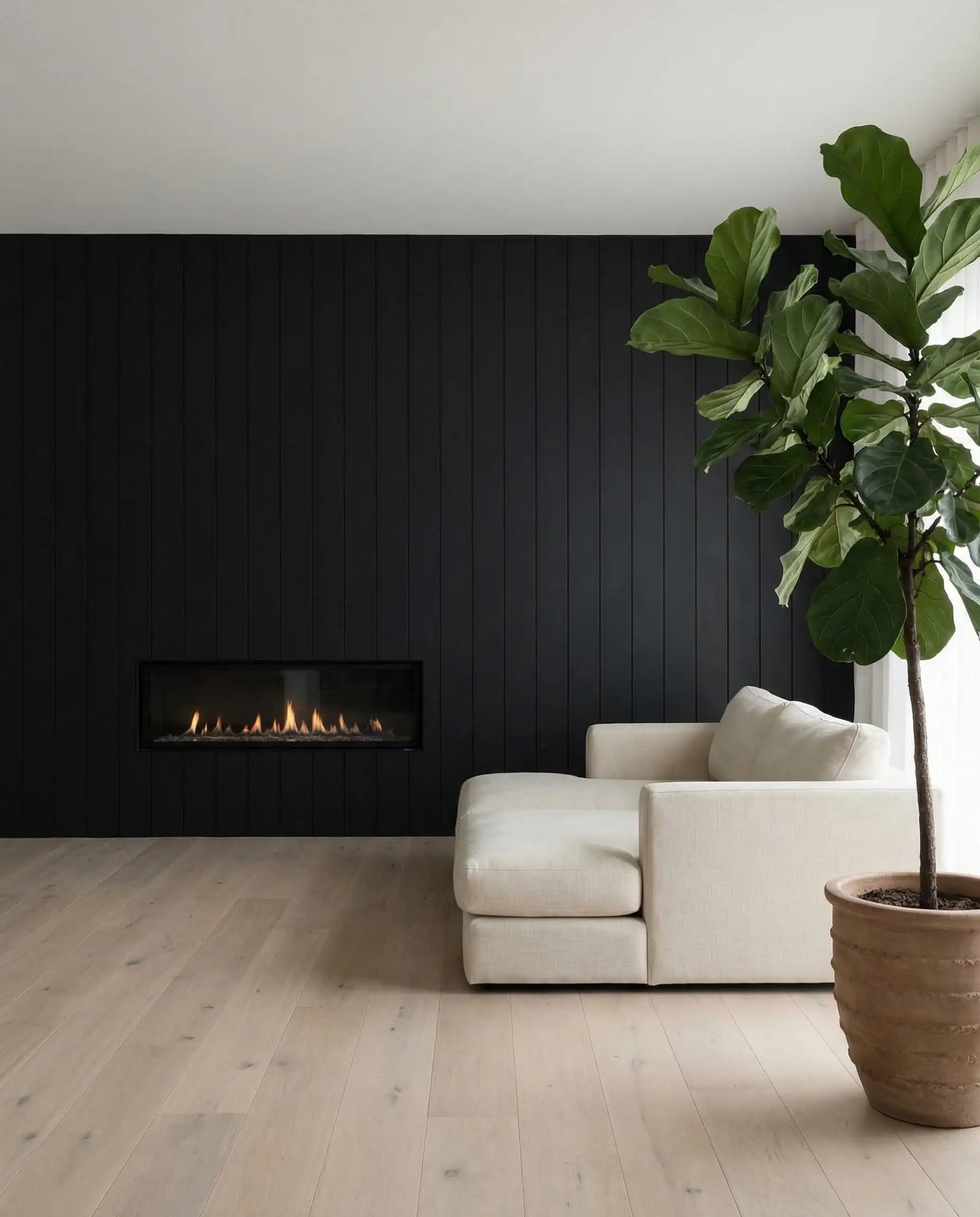 Minimalist Japandi living room with a sleek vertical black wood wall, linear fireplace, and fiddle leaf fig tree.