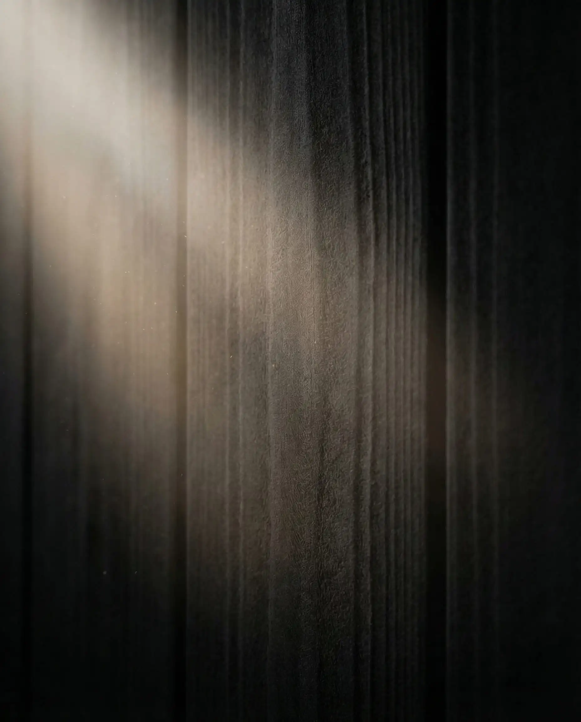 Extreme close-up of "dead flat" matte black paint on wood shiplap showing zero reflection.