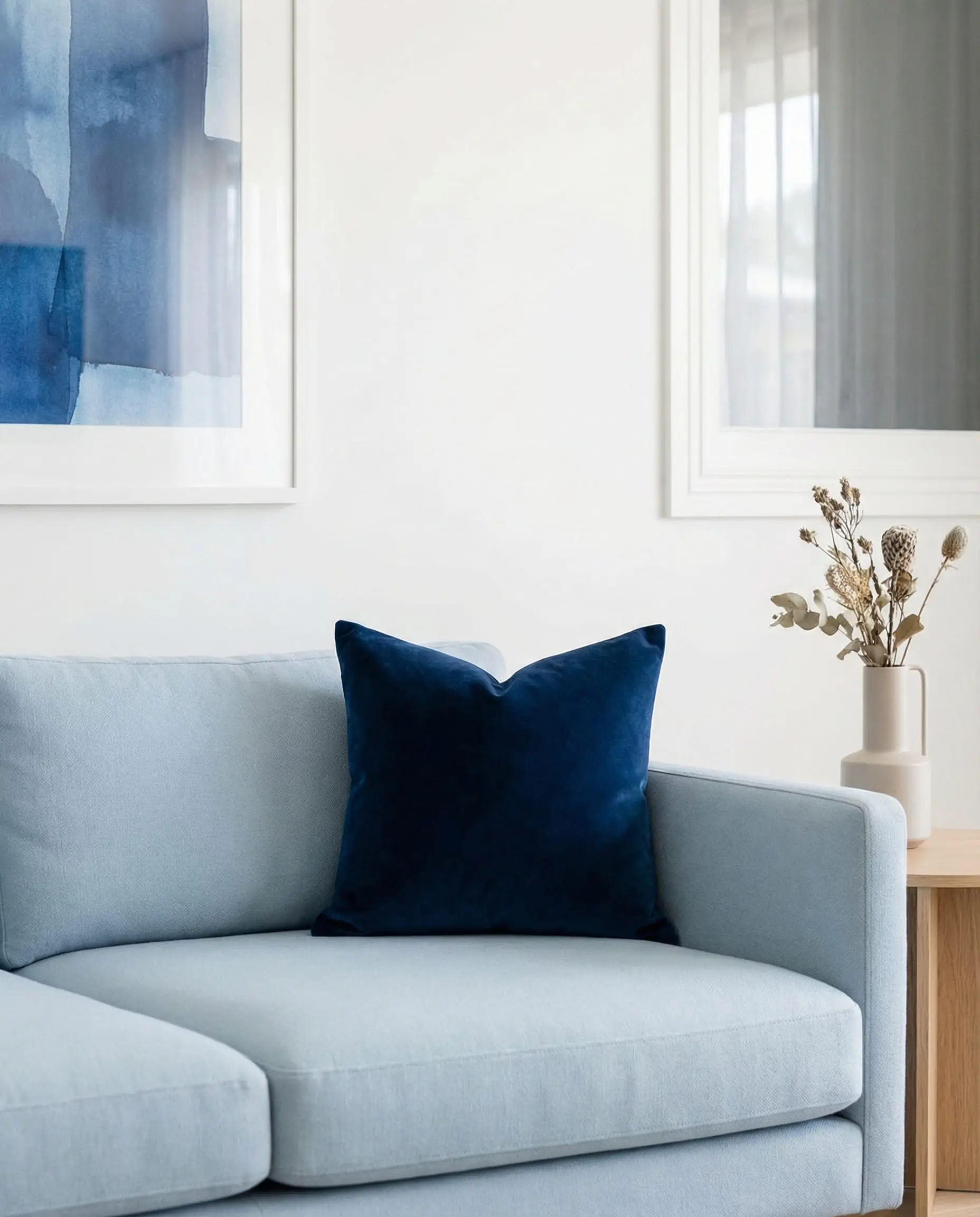 Light blue sofa anchored with a dark midnight blue velvet pillow.