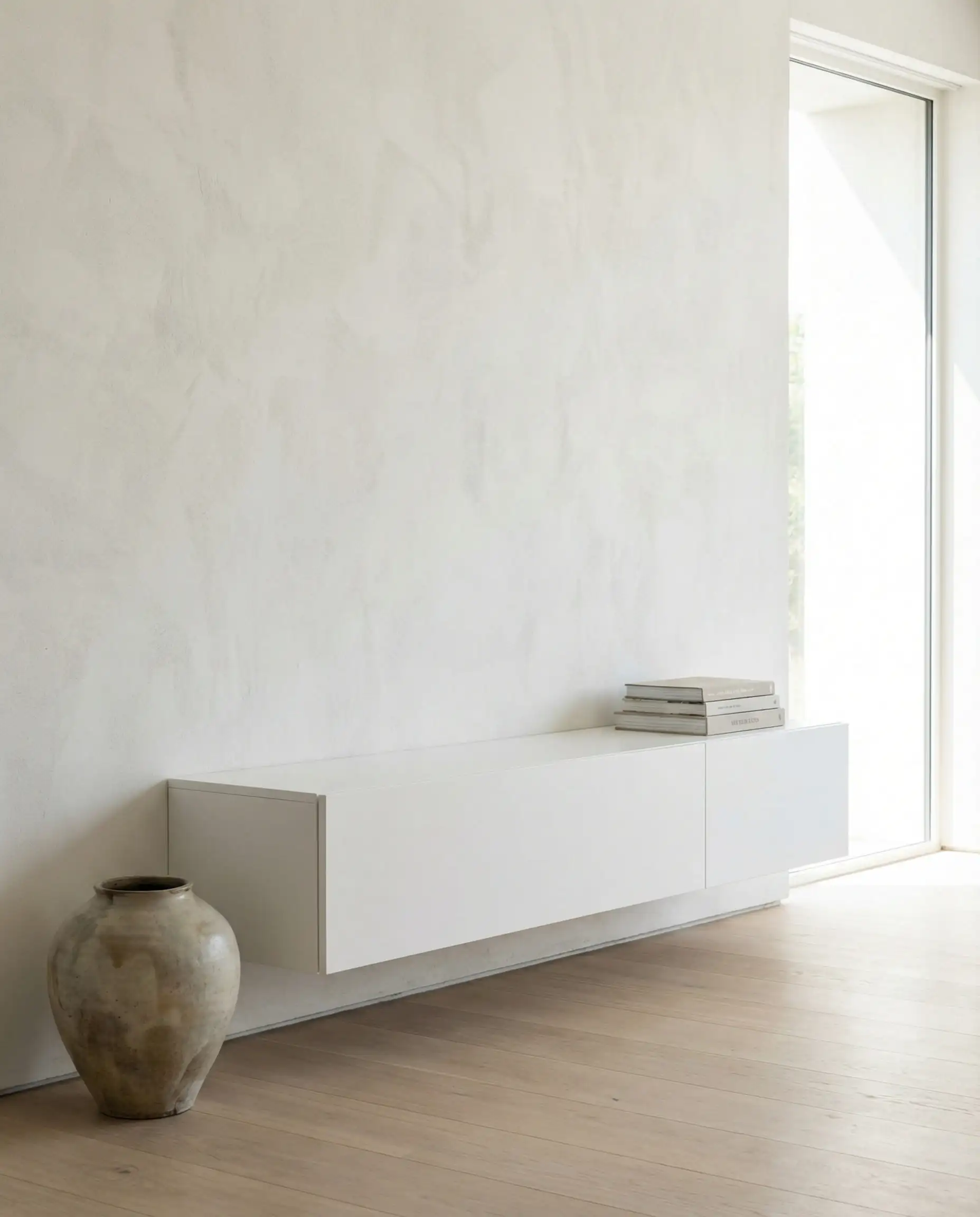 White floating media console on a textured plaster wall with completely hidden cables.