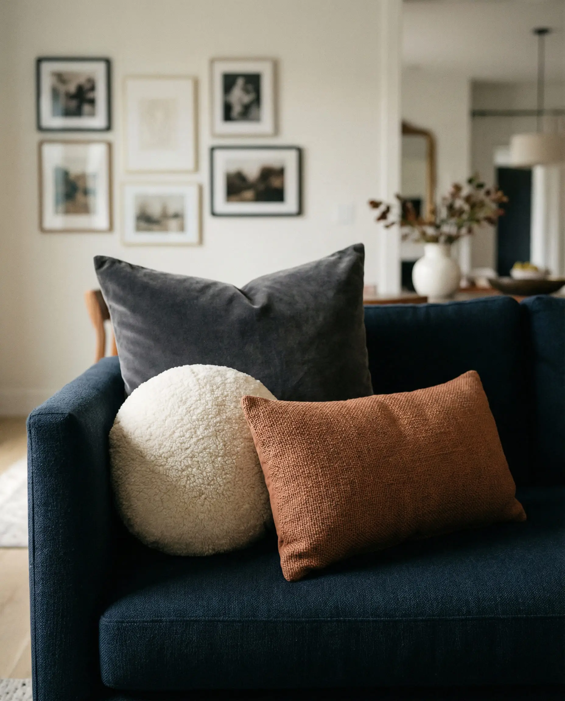A styling guide showing a blue sofa with three pillow shapes: a large square, a round shearling orb, and a rectangular lumbar.