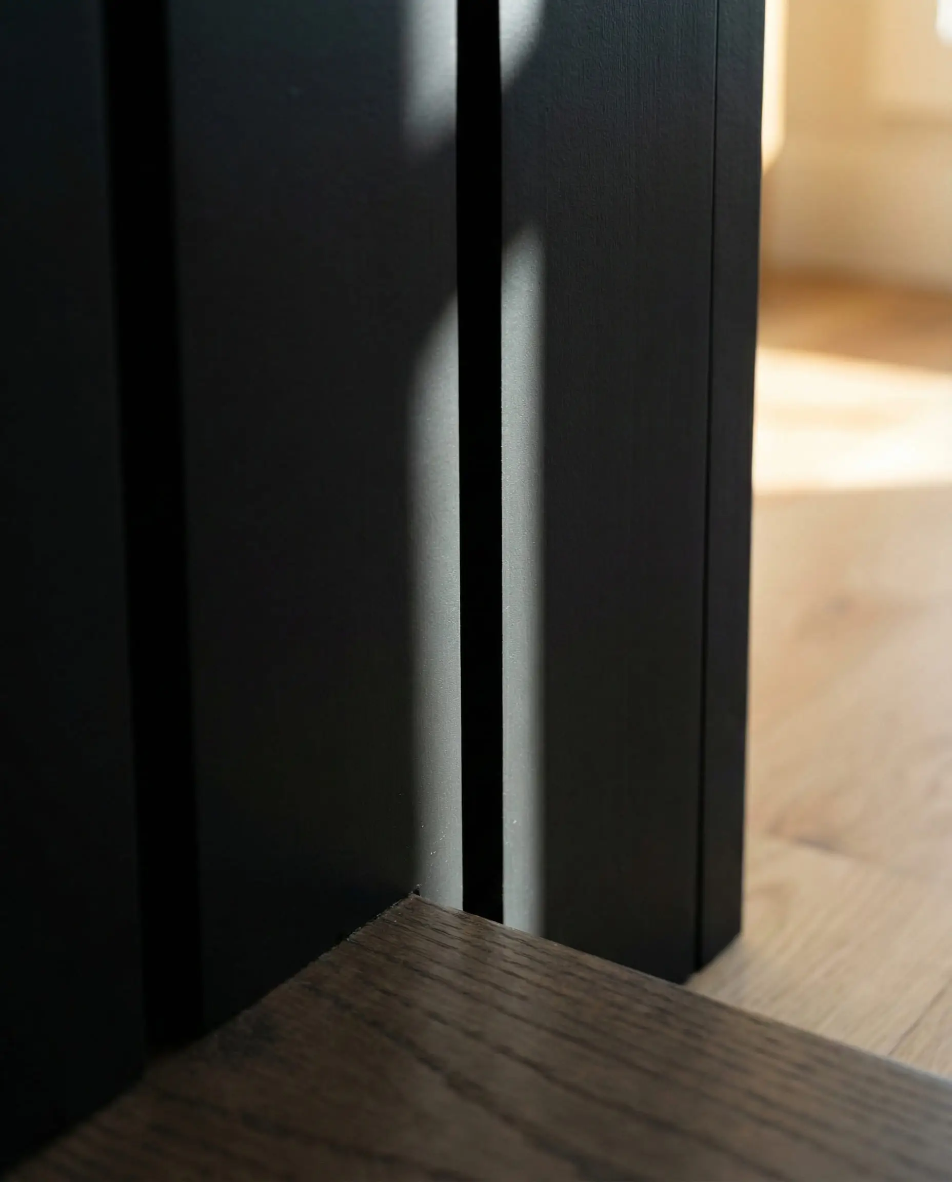 Close-up comparison showing the tight nickel-gap spacing of modern vertical black siding.
