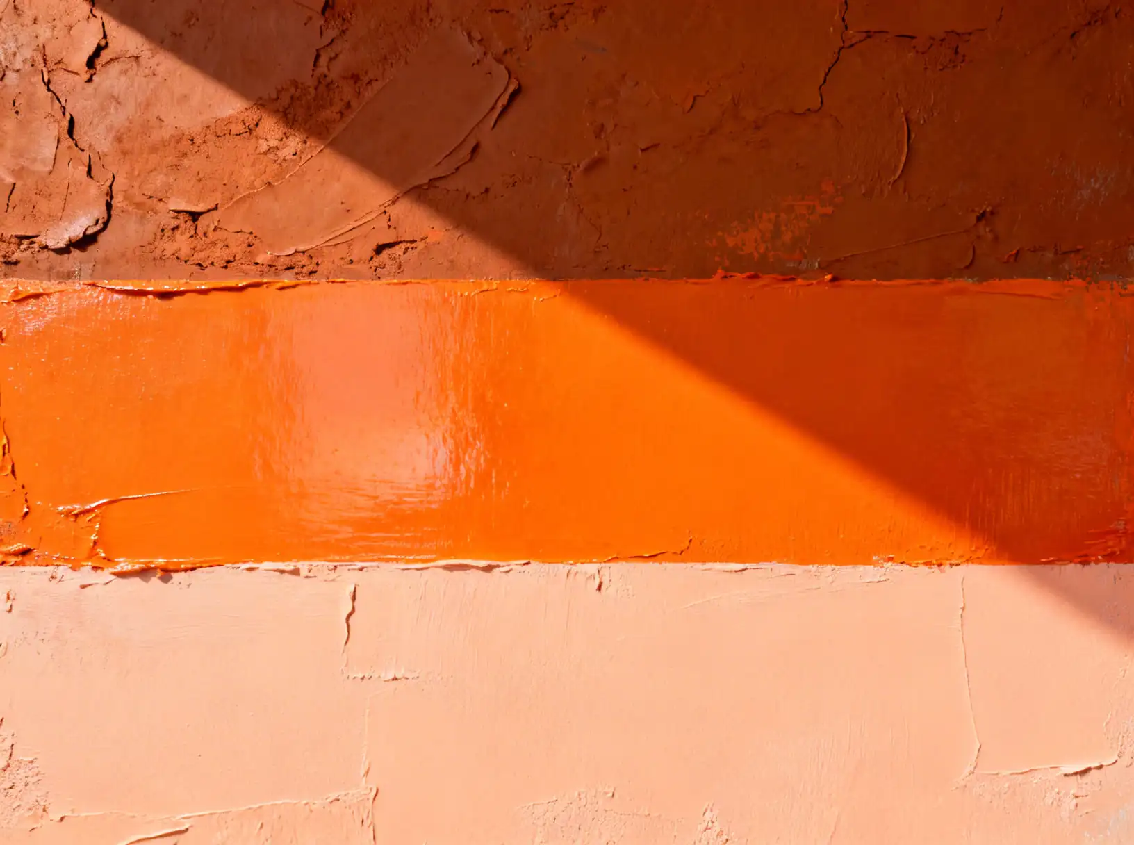 Color gradient flat lay showing three textures of orange wall paint: deep earthy terracotta, bright tangerine zest, and soft pastel peach plaster.