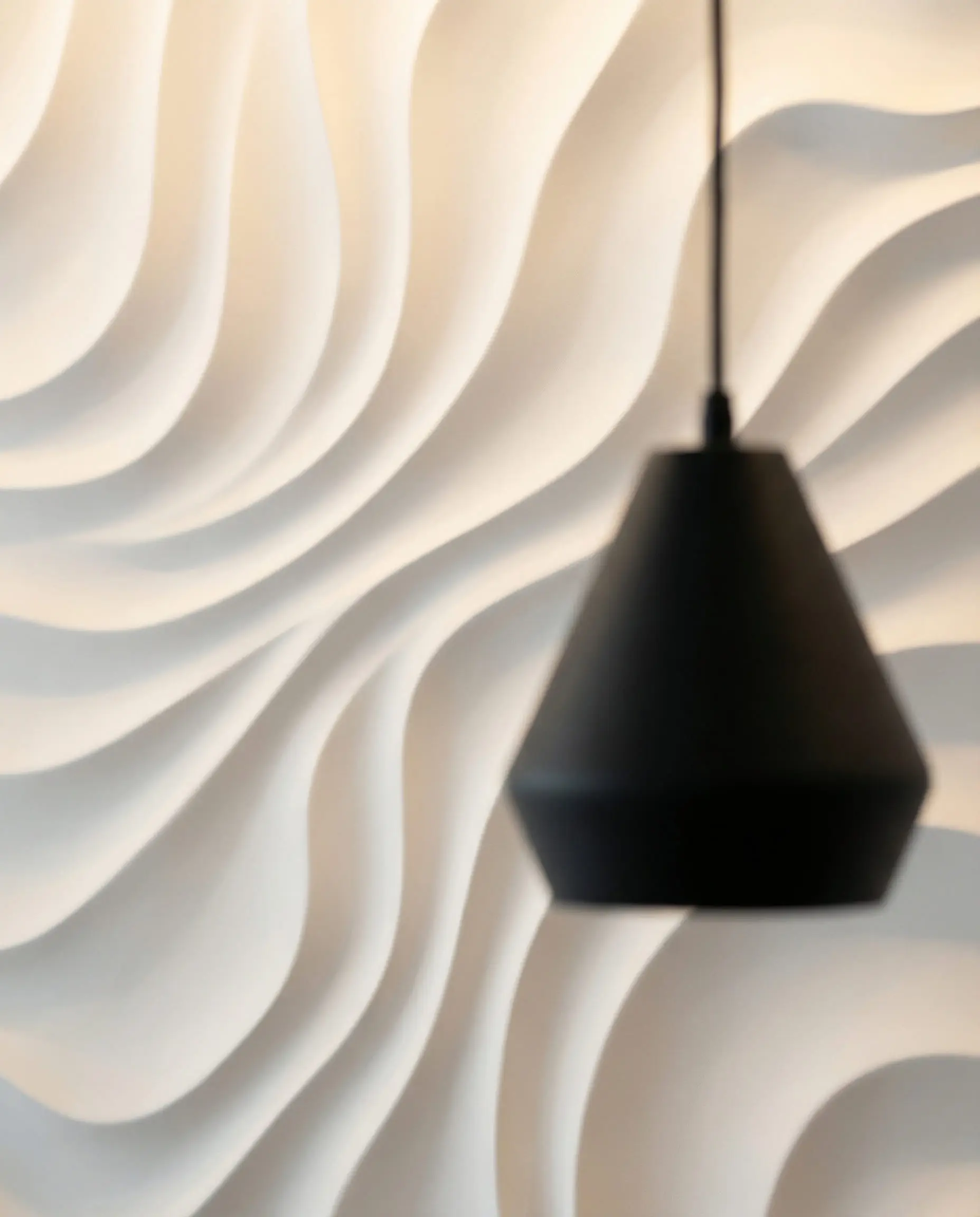 Macro shot of organic, fluid 3D wall panels resembling rippling water in pure white, with a modern black pendant light.