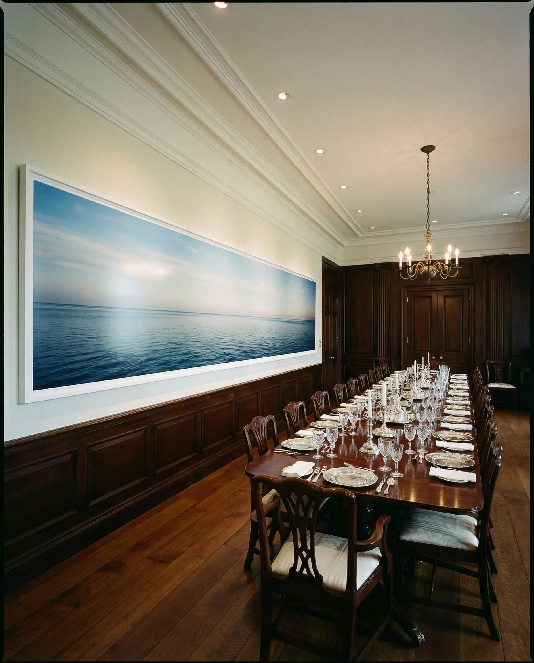 Long rectangular mahogany dining table paired with a wide panoramic landscape photograph on the wall.