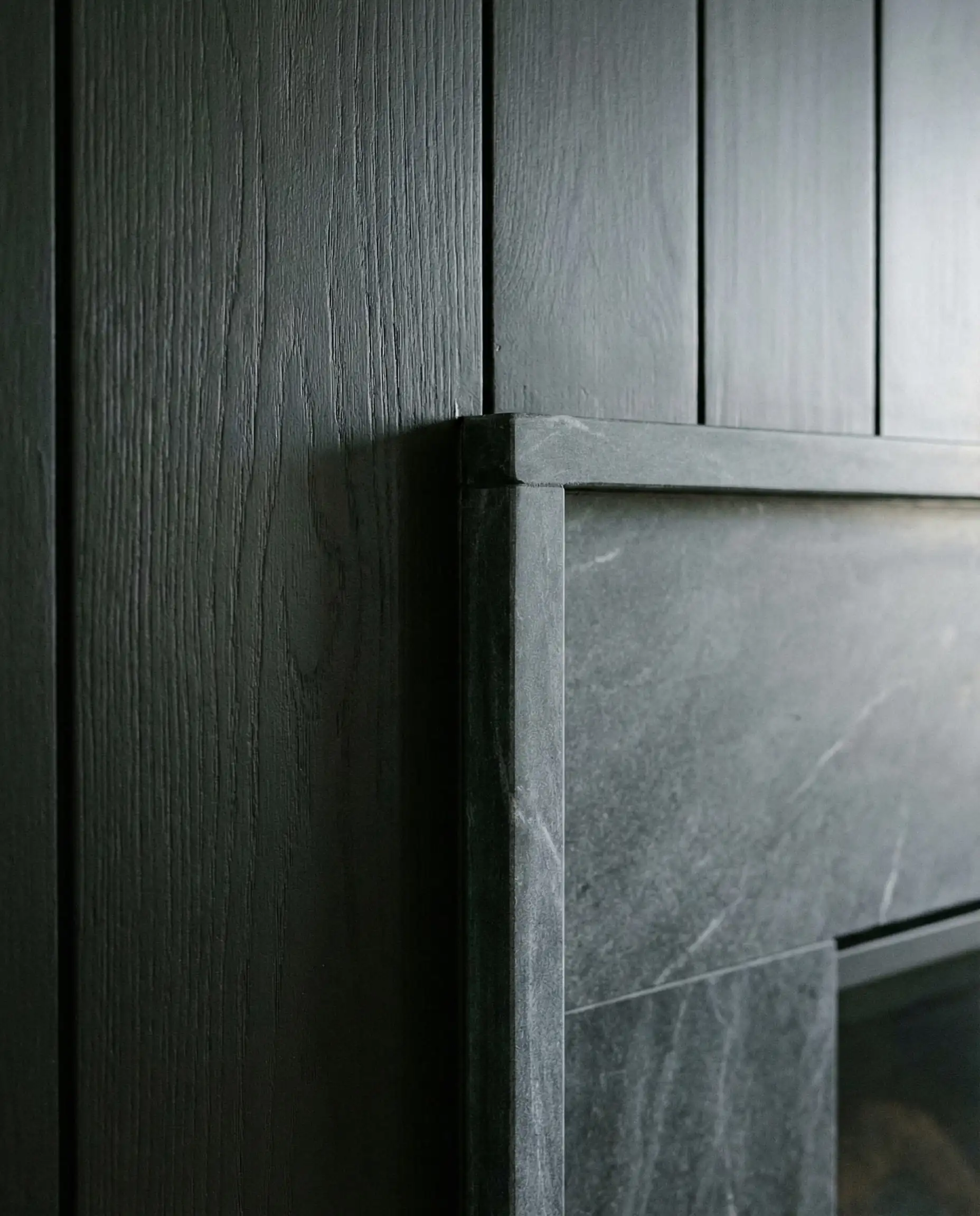 Texture detail showing the meeting point of matte black wood and honed charcoal soapstone.