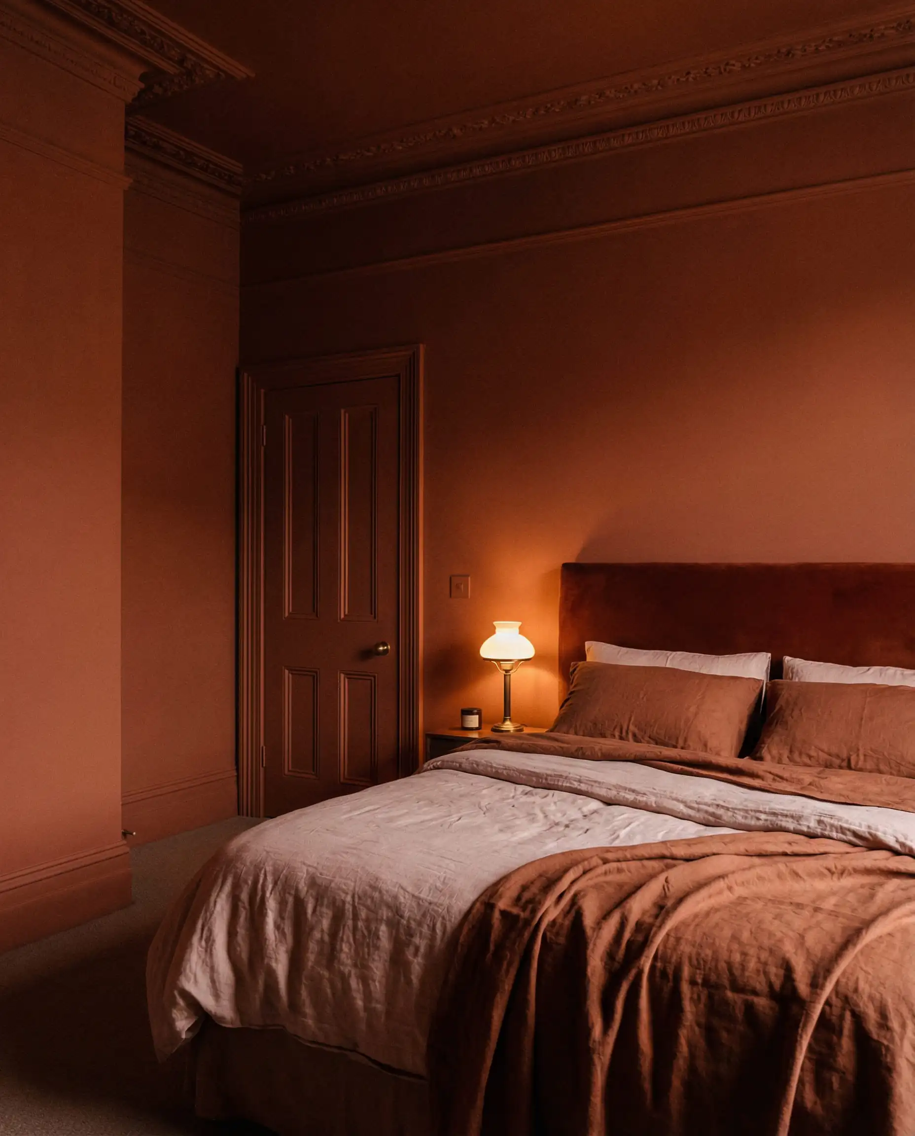 Small bedroom with walls, ceiling, and trim painted in deep terracotta (Color Drenching).